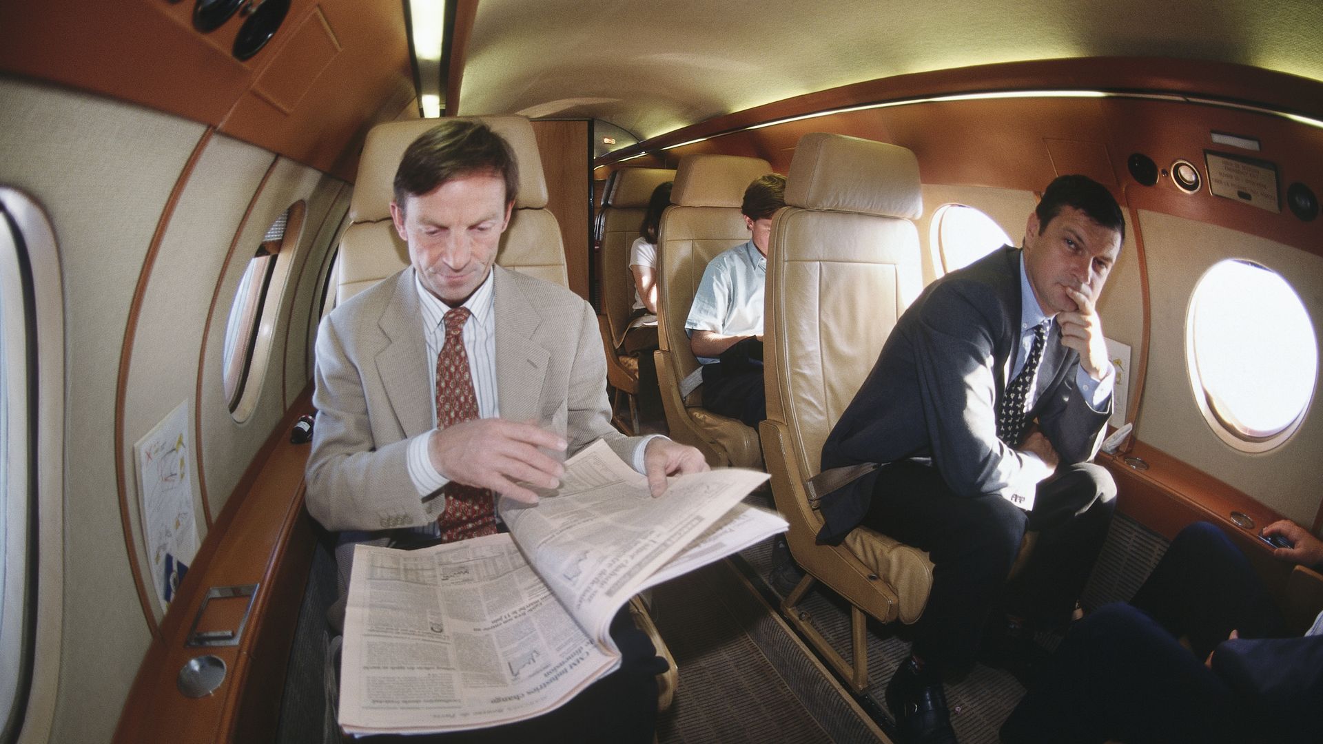 Man reading newspaper on private jet