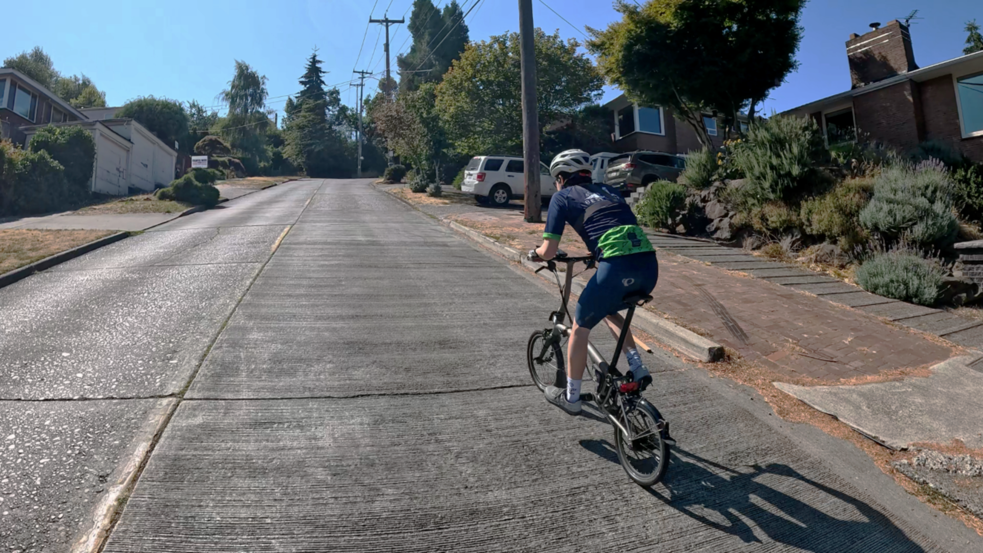 A bicyclist is seen from the back tackling a steep hill. 