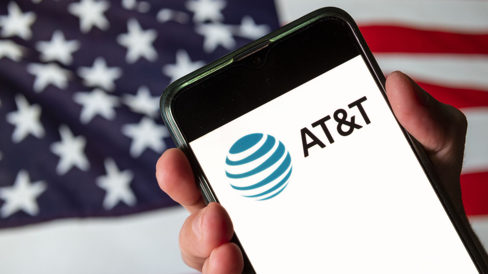 A phone displaying the AT&T logo appears in front of the American flag.