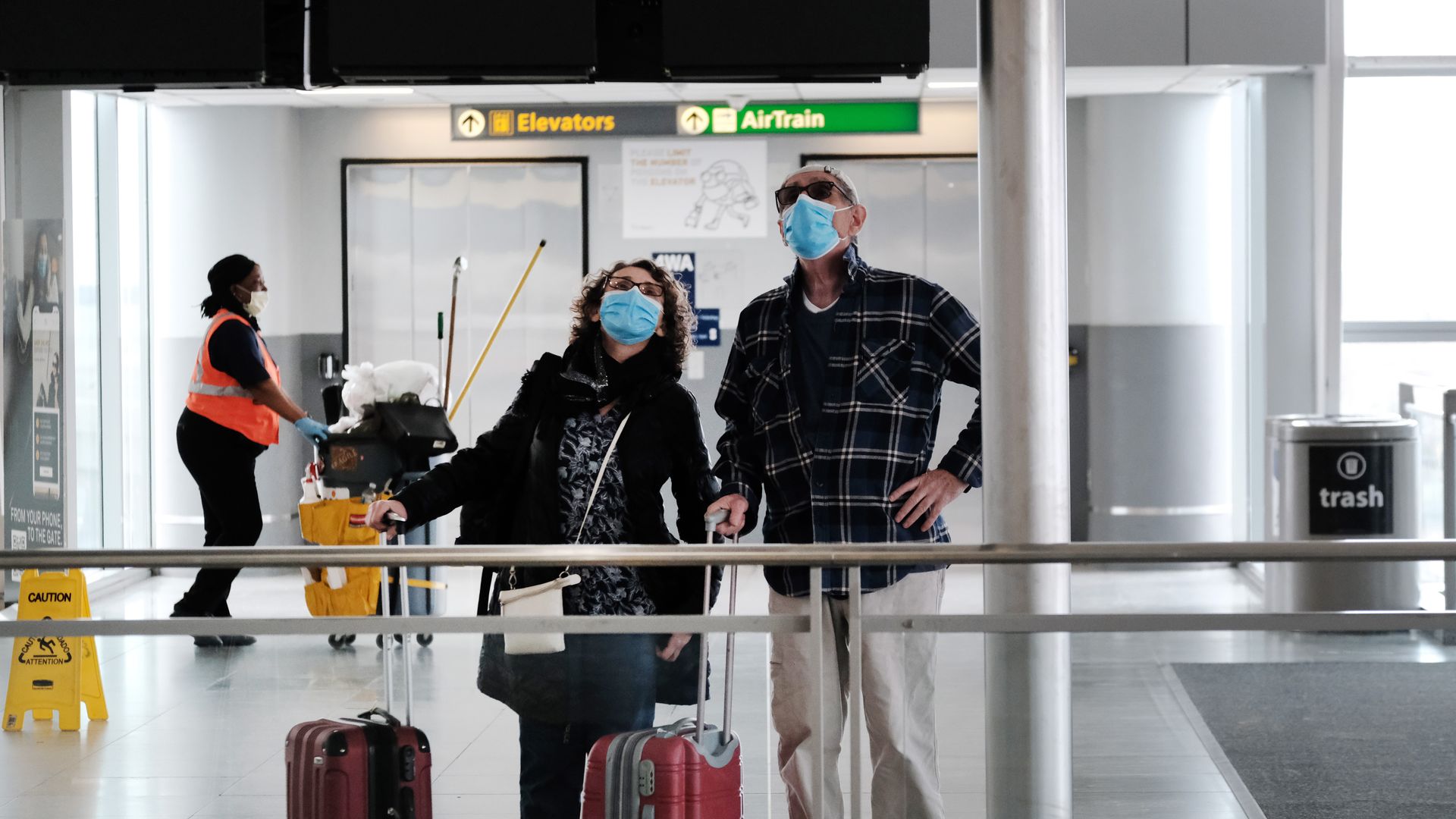  Travelers wearing masks look up at a sign inside John F. Kennedy Airport on April 19, 2022 in New York City. 
