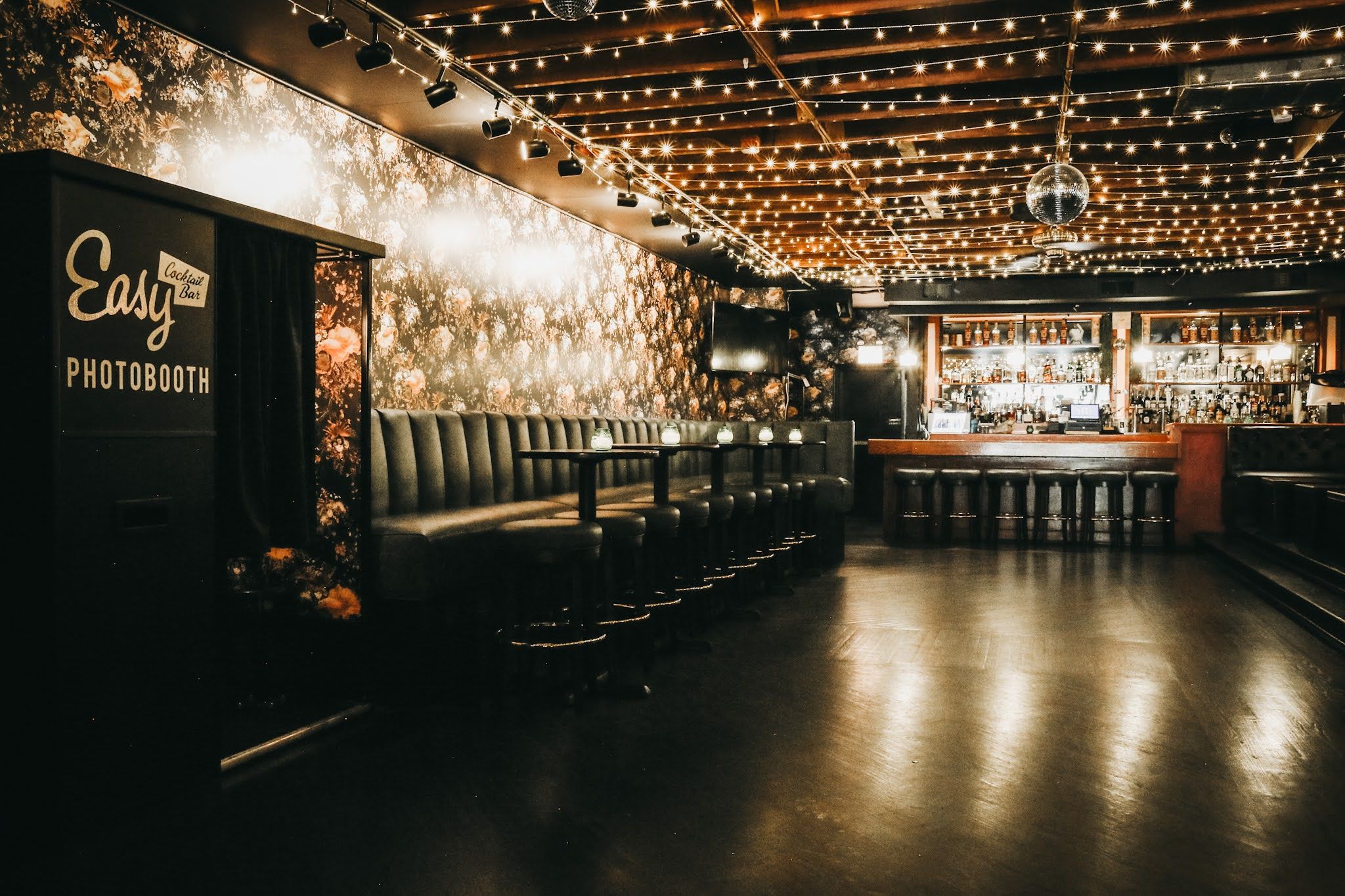 Empty bar with string lights on the ceiling, booths against the wall and a photobooth