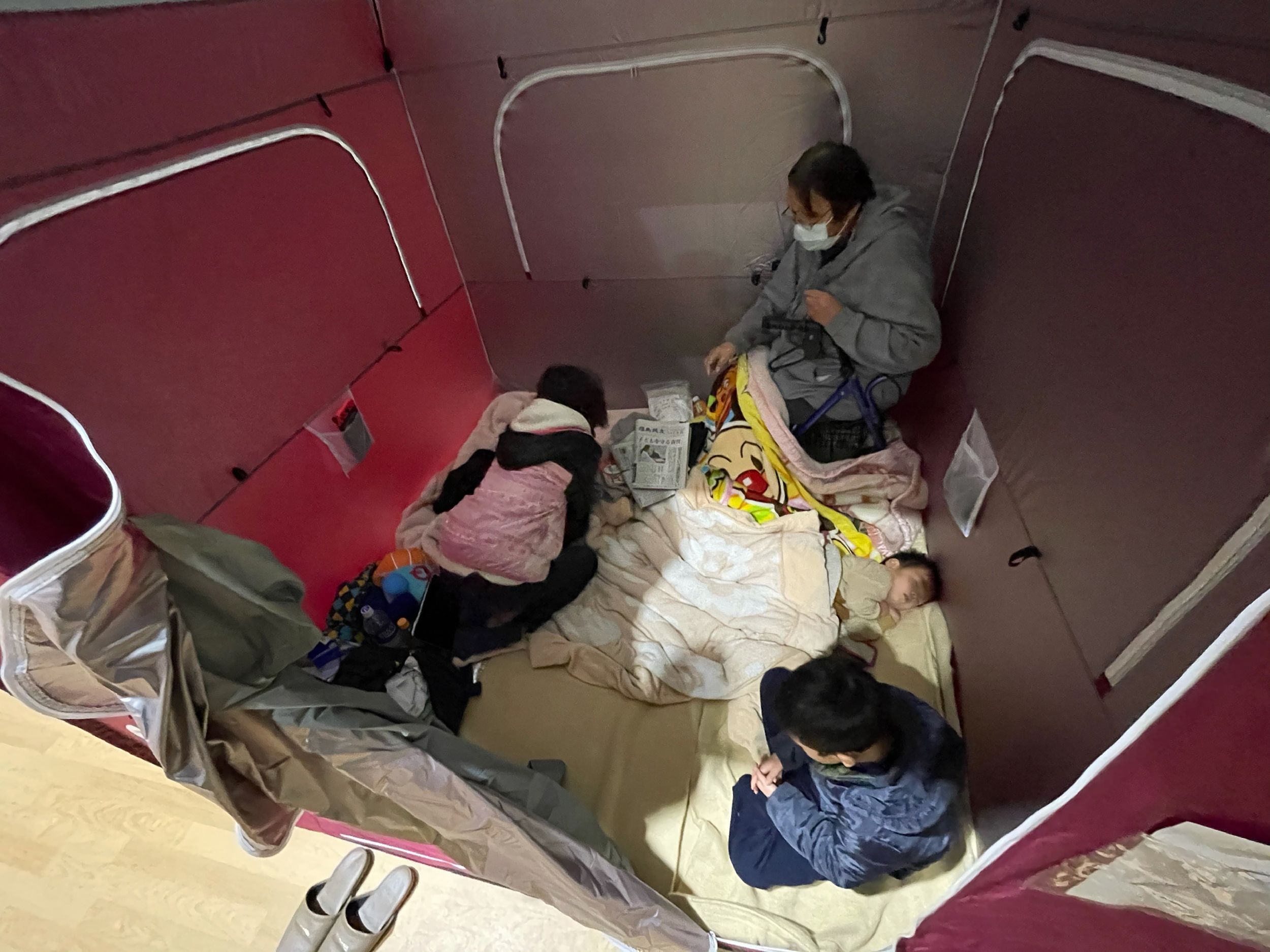 An evacuated family rests at a shelter set up in a sports arena in Soma, Fukushima prefecture on February 14