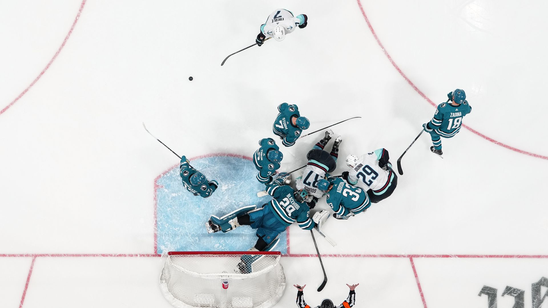 Birds-eye view of a collision during a hockey game that left players sprawled on the ice.