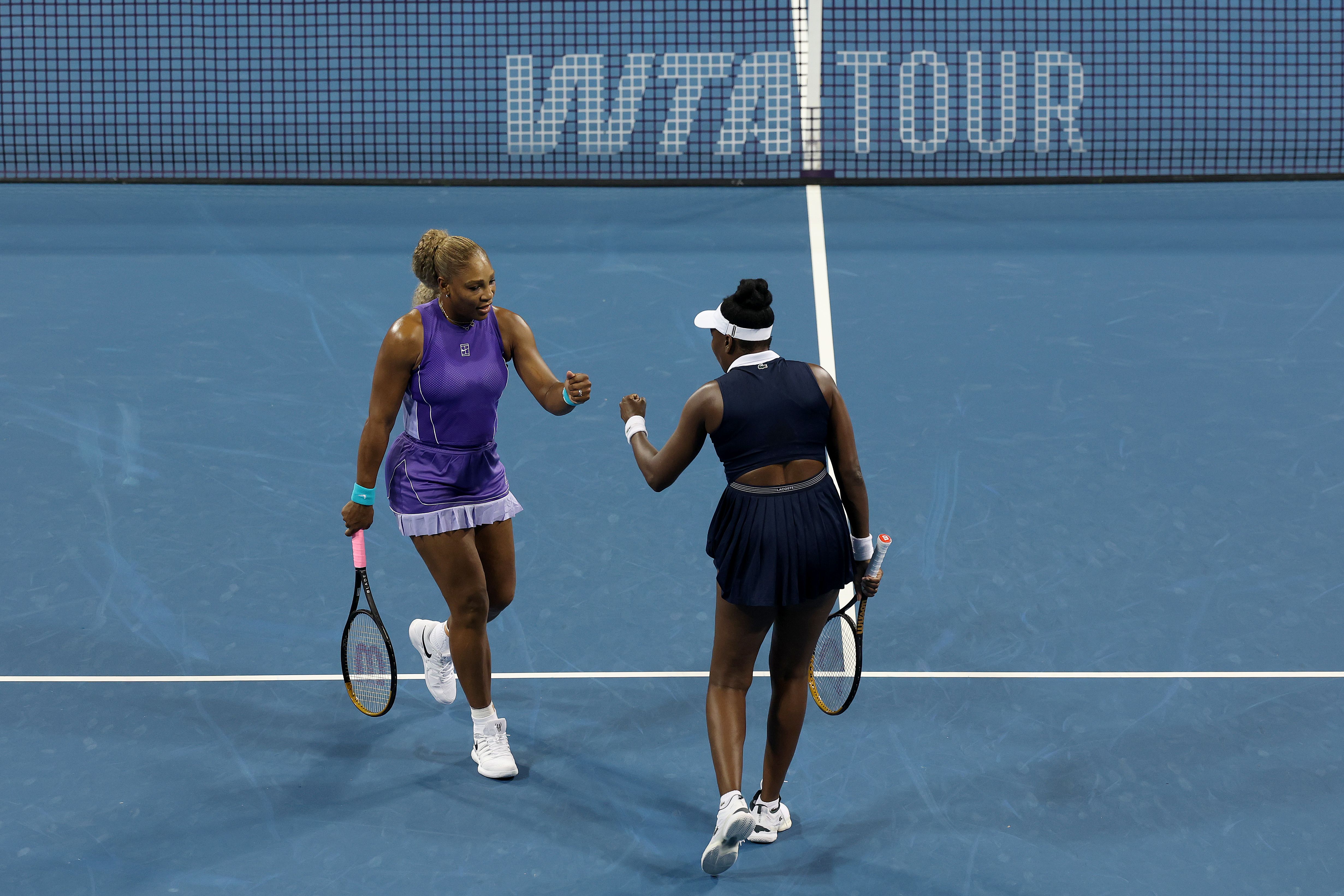 Serena and Venus Williams fist bump each other on the court