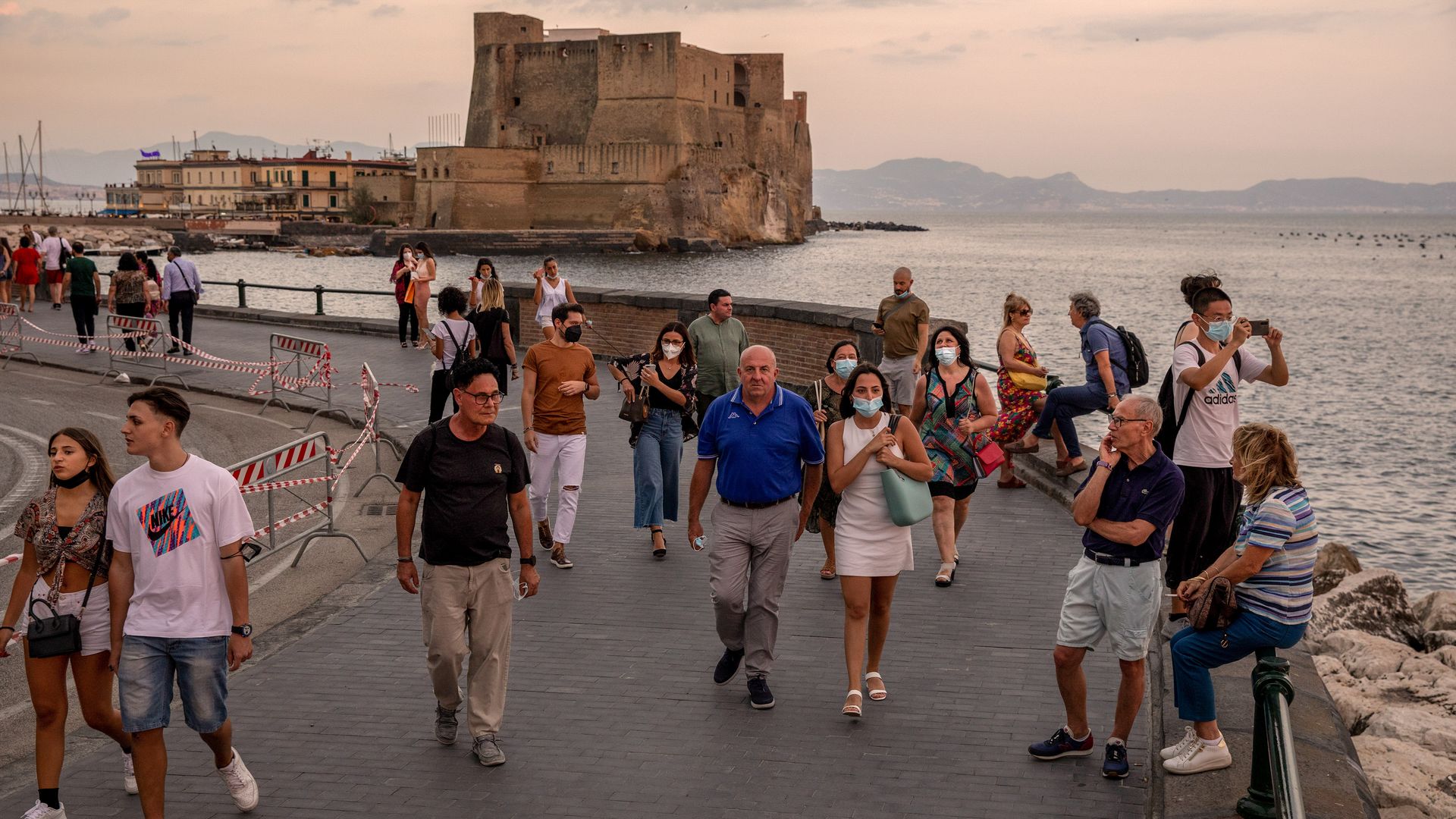 Tourists walk along the promenade near Ovo Castle, also known as Castel dell'Ovo, seaside fortification in Naples, Italy, on Wednesday, July 21, 2021.