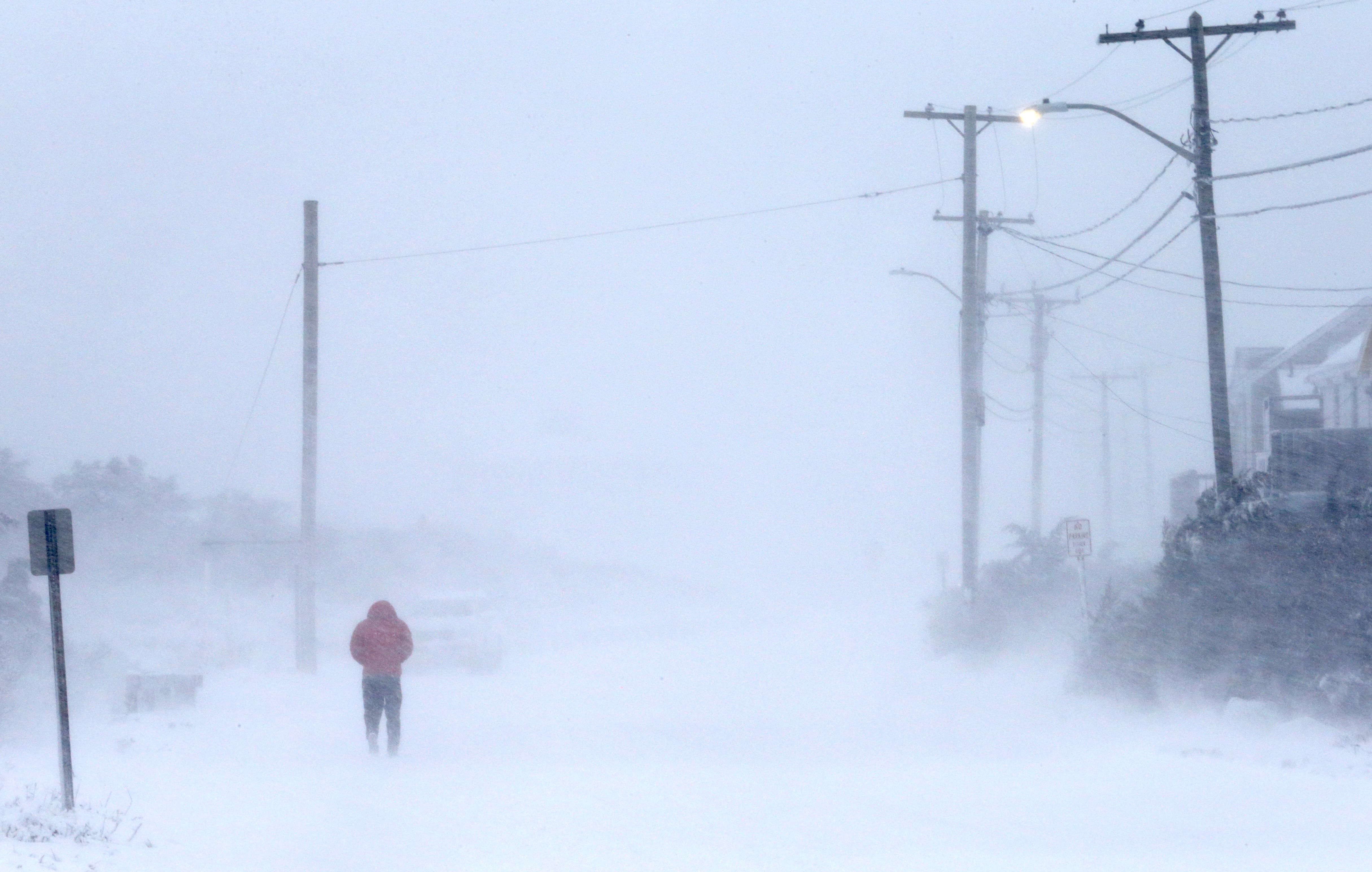 A man walks along Surf Drive in whiteout conditions during the snowstorm in Falmouth, MA on Jan. 29, 2022