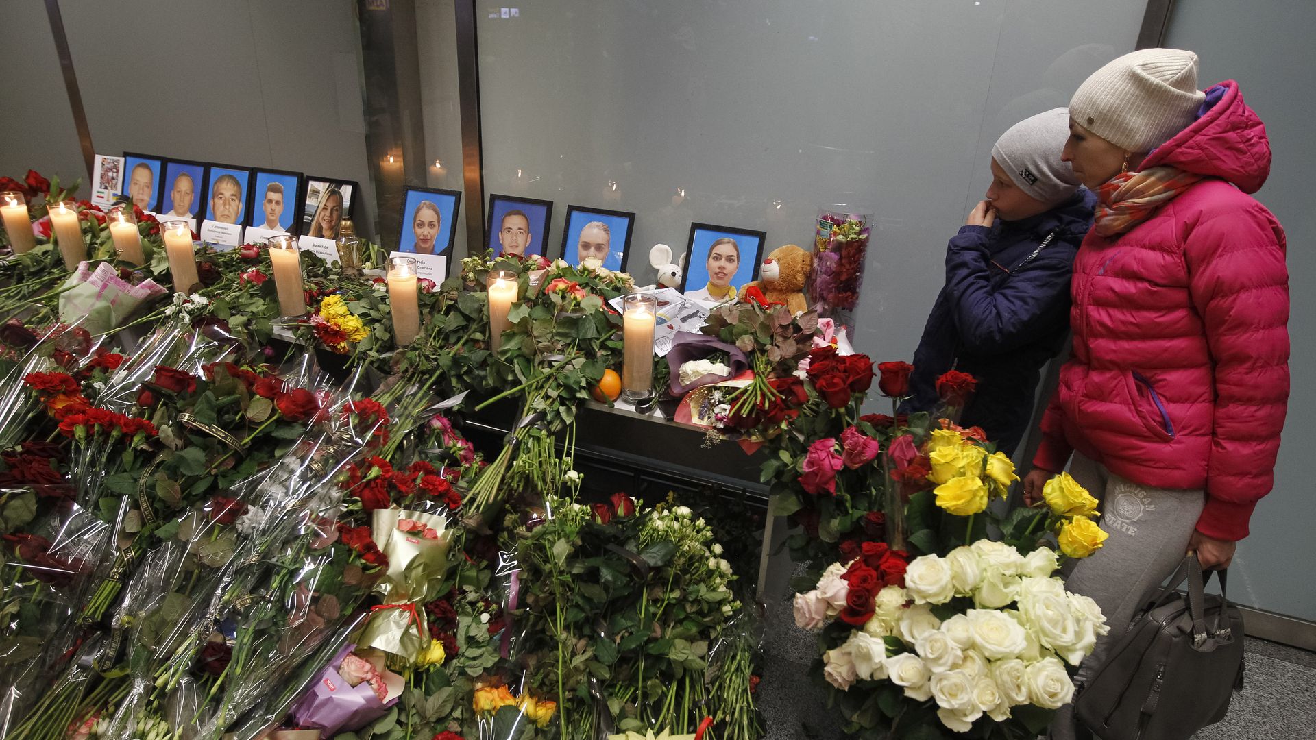 A woman and child look onto a memorial surronded by flowers for the passengers and crew of Ukrainian Boeing 737