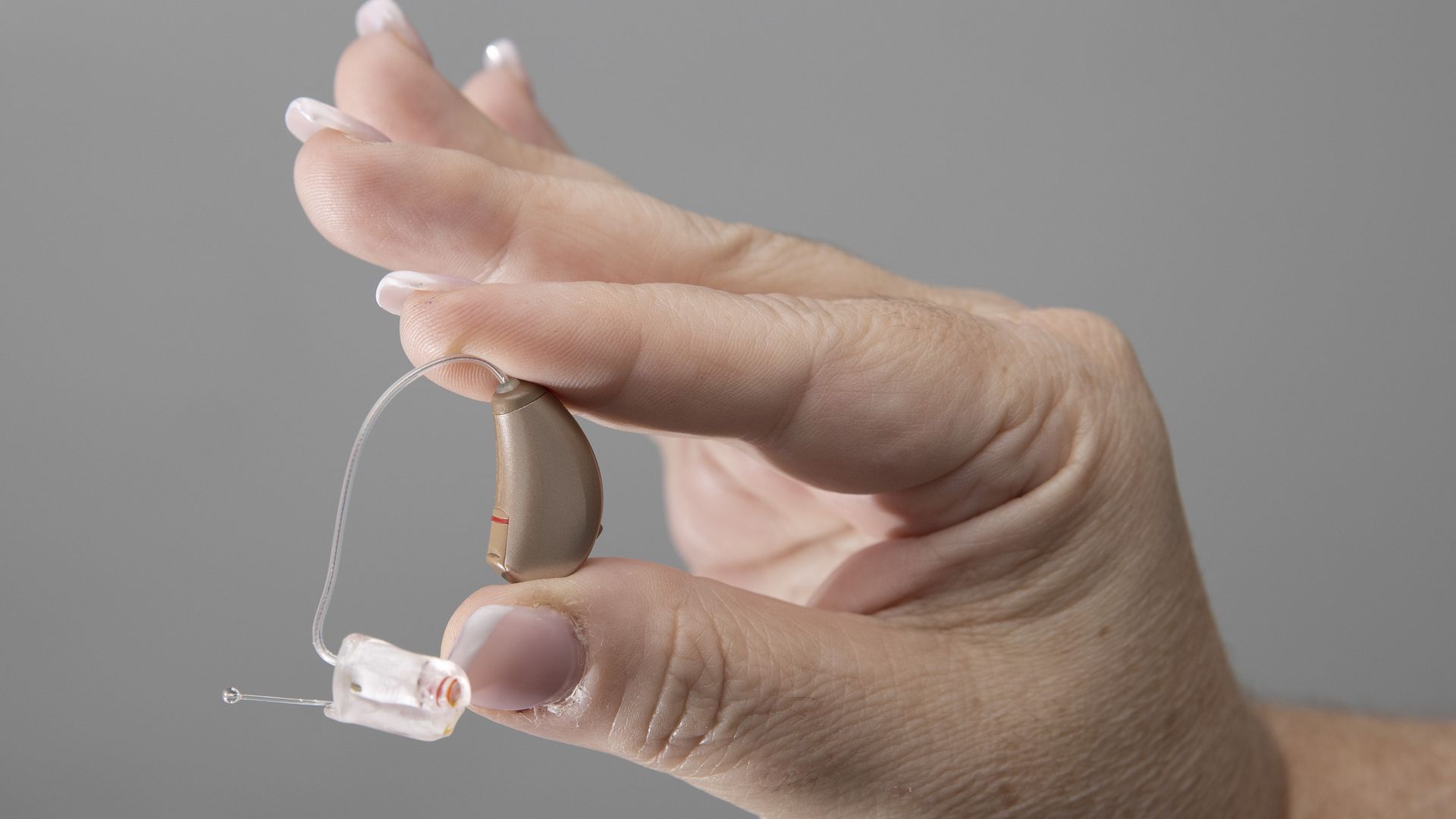 A hand holding a hearing aid