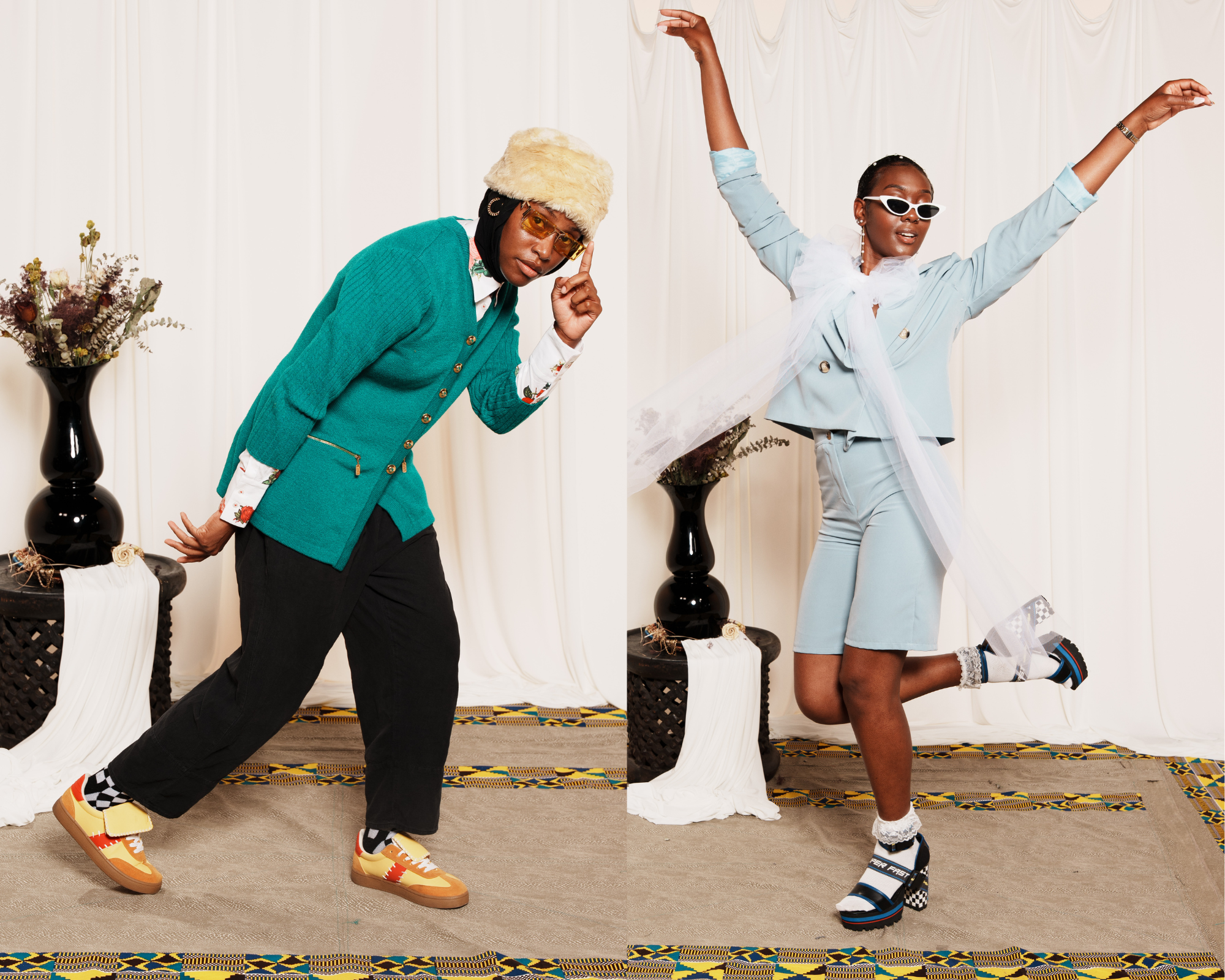 Two fashionably dressed people pose indoors with white curtains background; left person in teal cardigan, black pants, yellow shoes, fur hat; right person in light blue suit shorts, white scarf, heels, and white sunglasses.