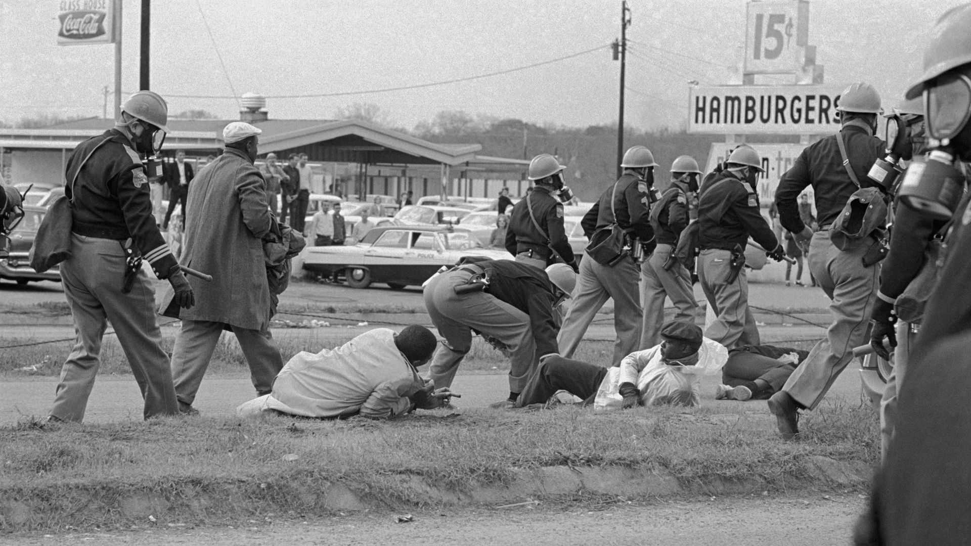 Historical photo of civil rights protesters in 1965 Selma, Alabama, injured on the ground and being ignored by passing police