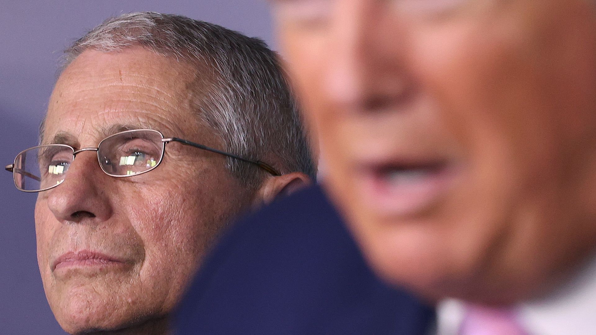 In this image, Fauci stands behind Trump