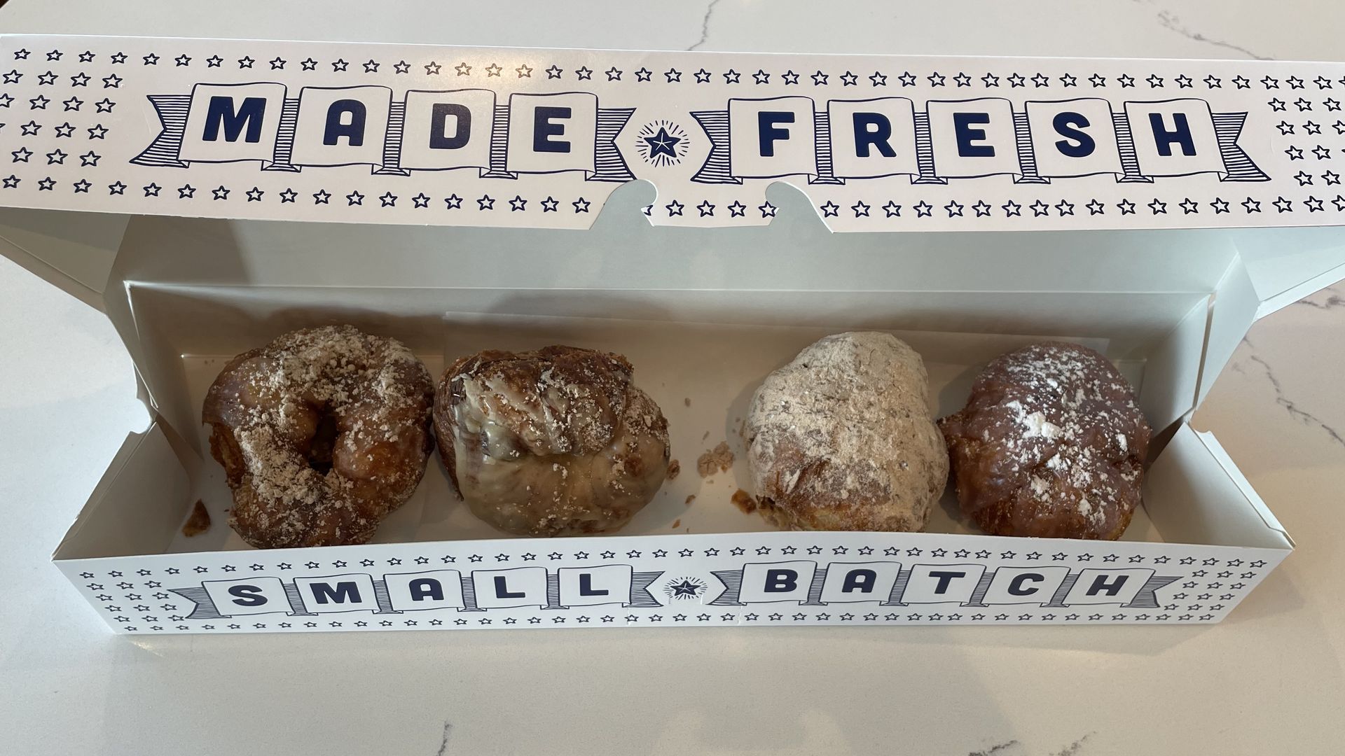 Four donuts from Parlor Doughnuts in a box.