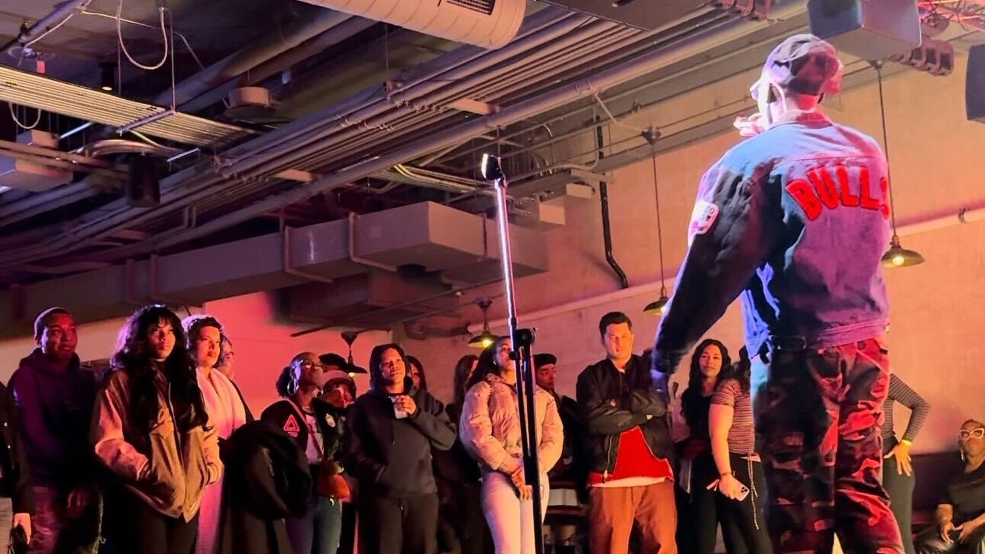 Person performing on stage wearing a Bulls jacket in front of a crowd.