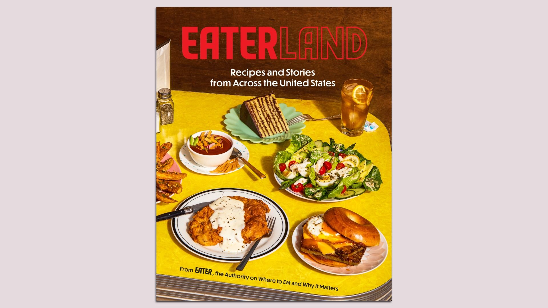 Cover of "EATERLAND": bold red title on a bright yellow table filled with assorted foods—salad, cake, fries, fried chicken, a burger, soup—and a glass of iced tea.