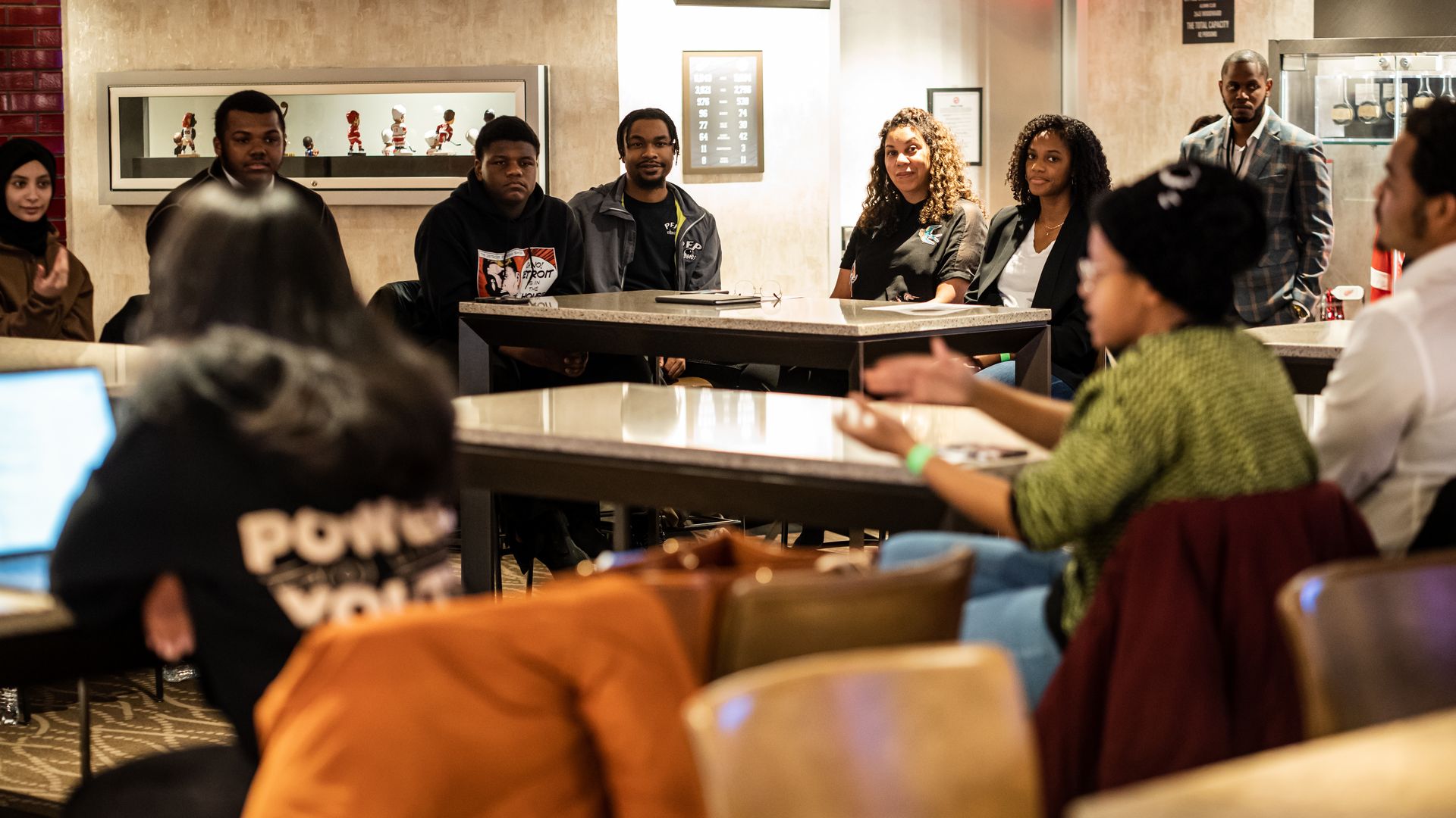 People sit at tables watching someone speak.