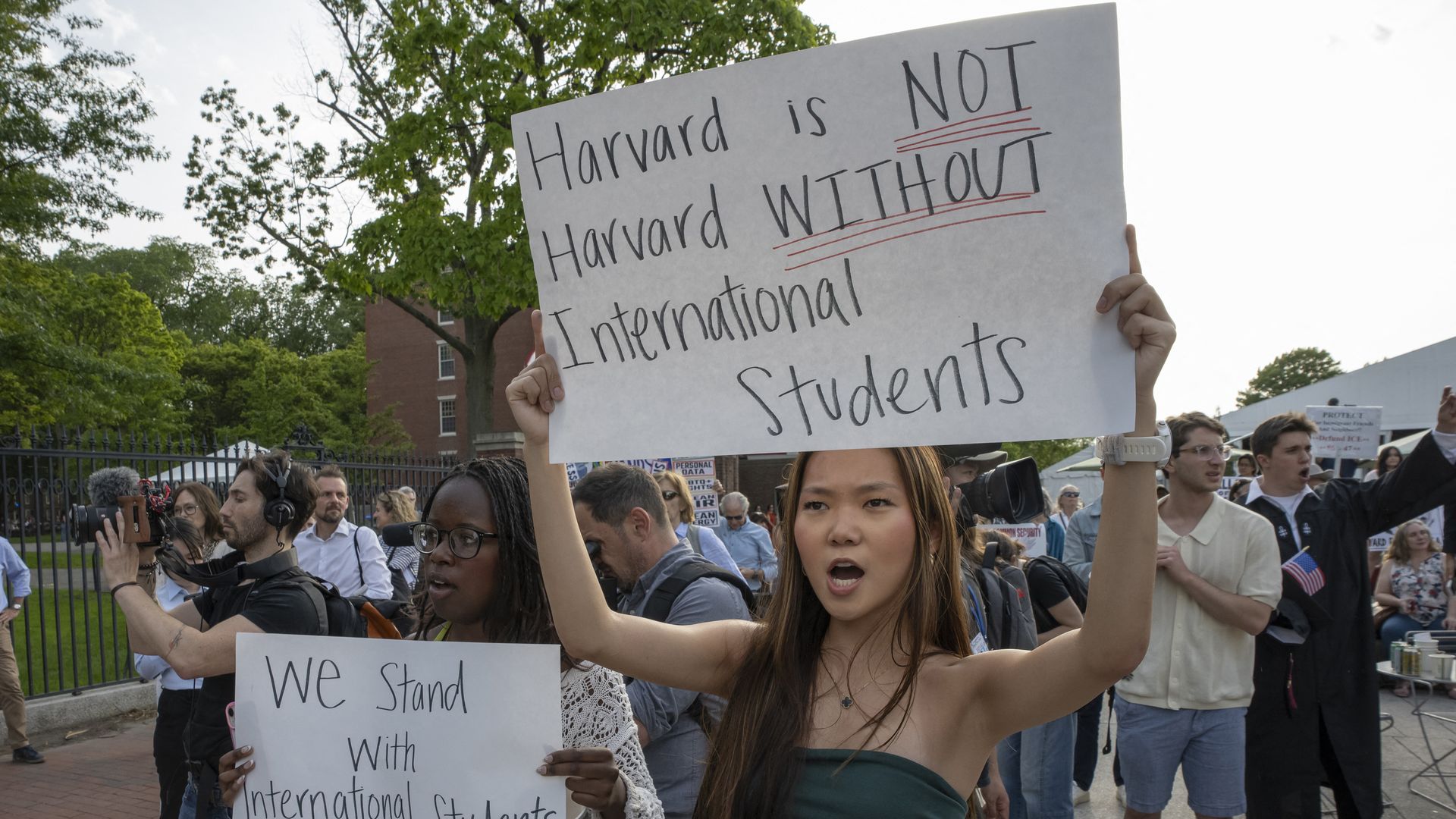 Protesters hold up signs advocating for international students at Harvard, one of which reads "Harvard is NOT Harvard WITHOUT International Students."