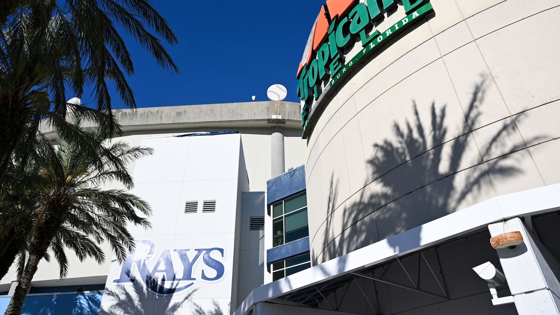 An exterior photo of Tropicana Field after it was damaged by Hurricane Milton. Its orange-and-green sign is visibly damaged in the picture.