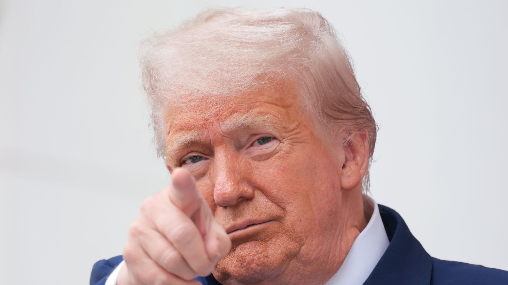 Donald Trump, wearing a blue suit, pointing.