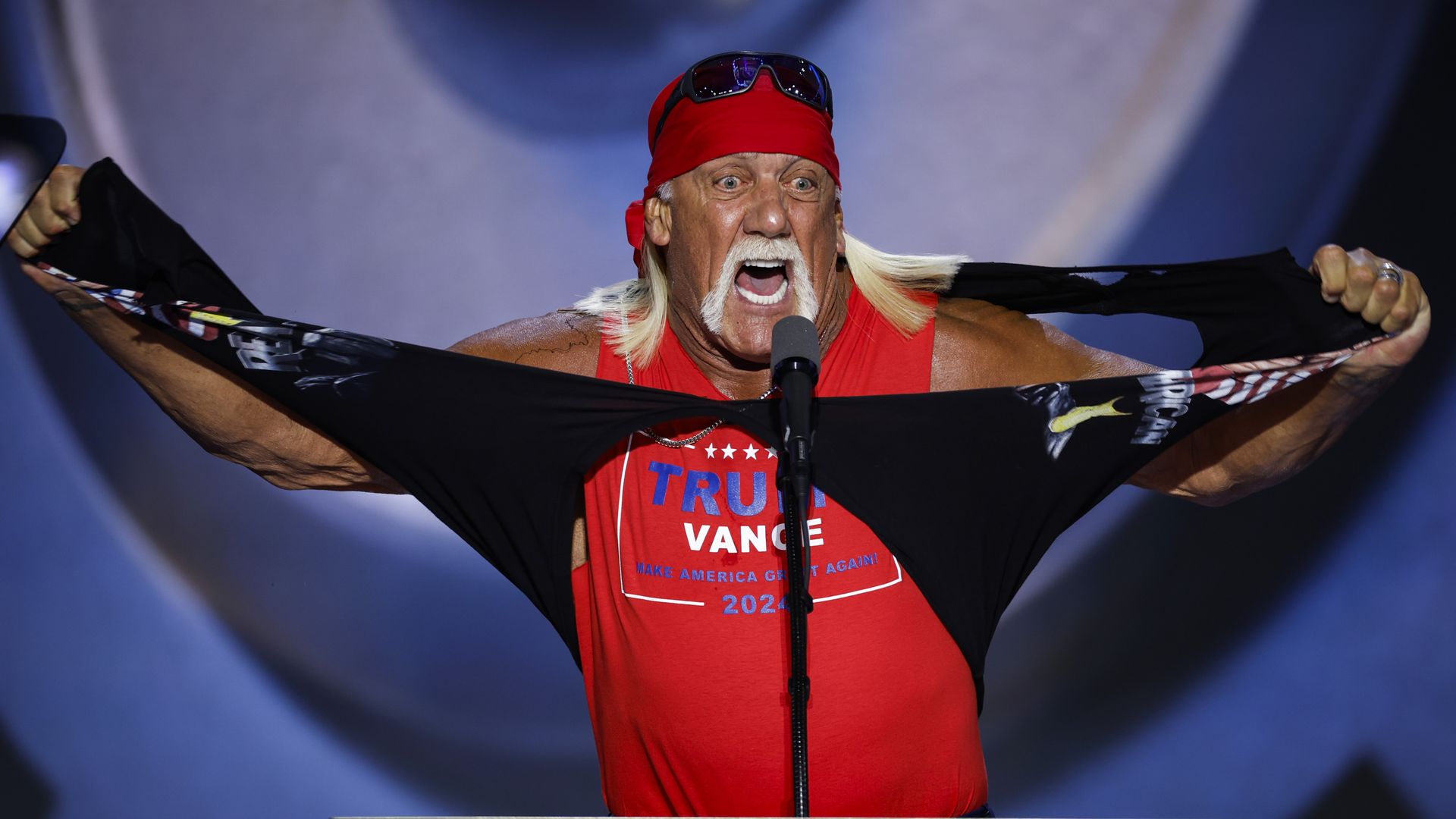 Hulk Hogan at a microphone ripping his shirt, revealing a Trump/Vance shirt beneath