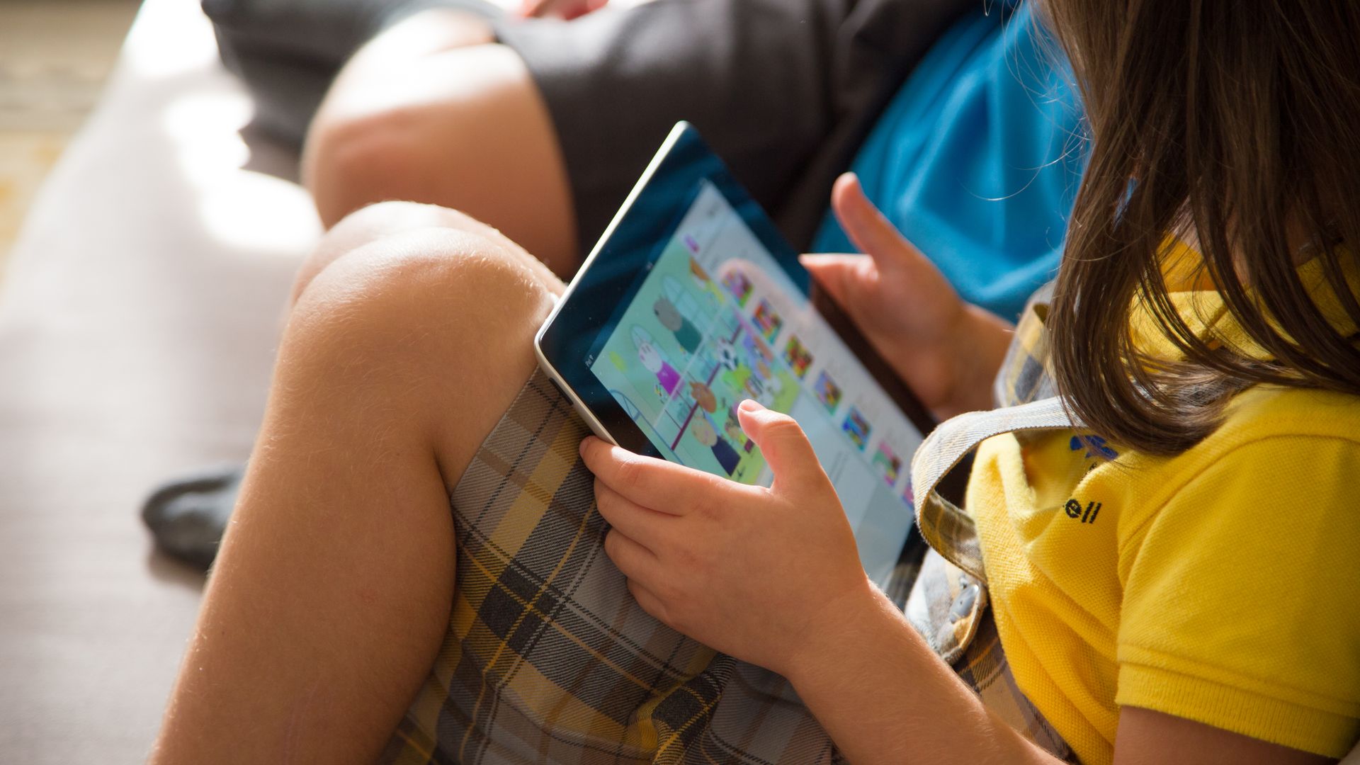 Two kids watch cartoons online on an iPad.