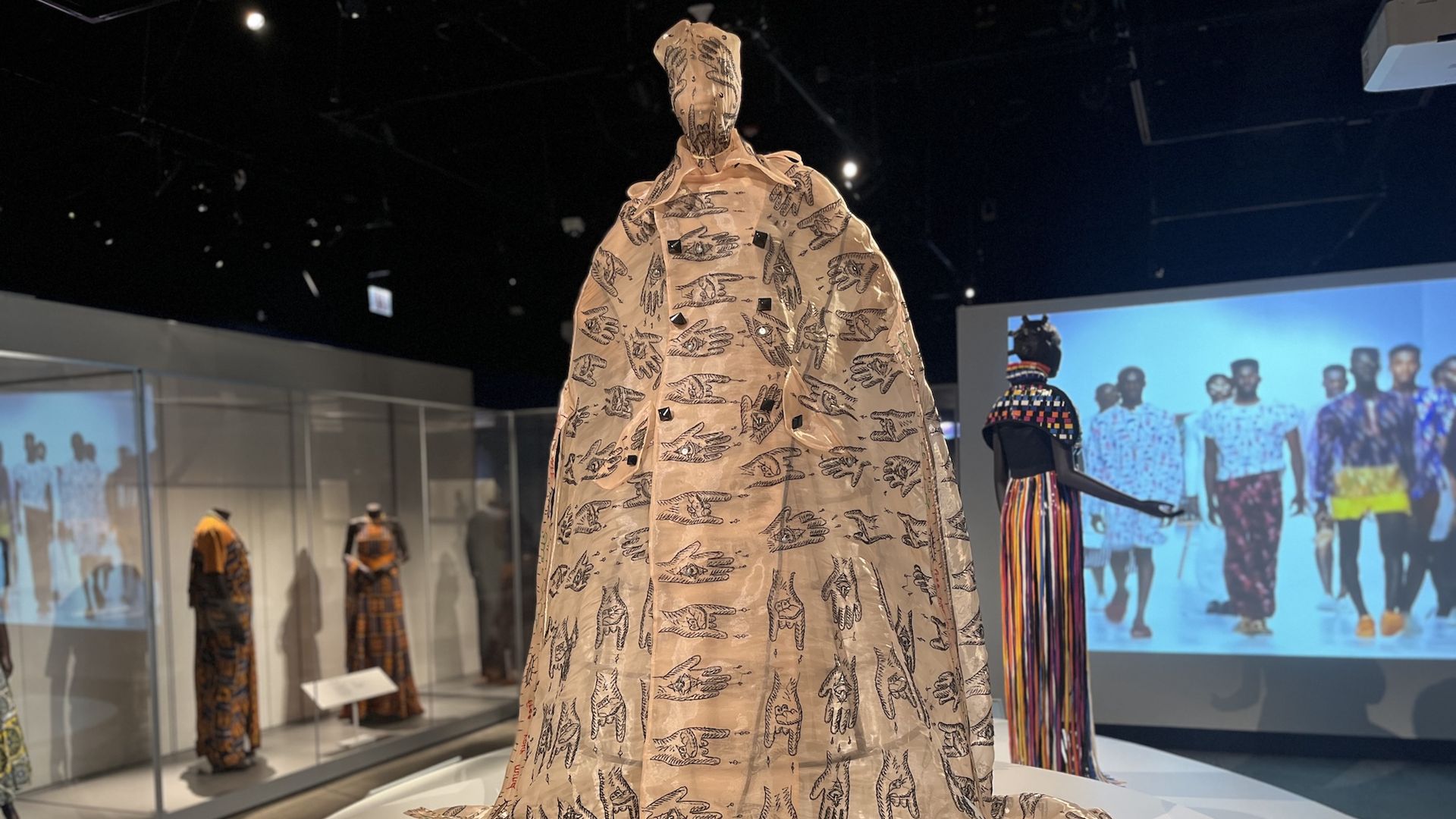Mannequin wearing a peach tulle gown that has black hands beaded onto the garment.