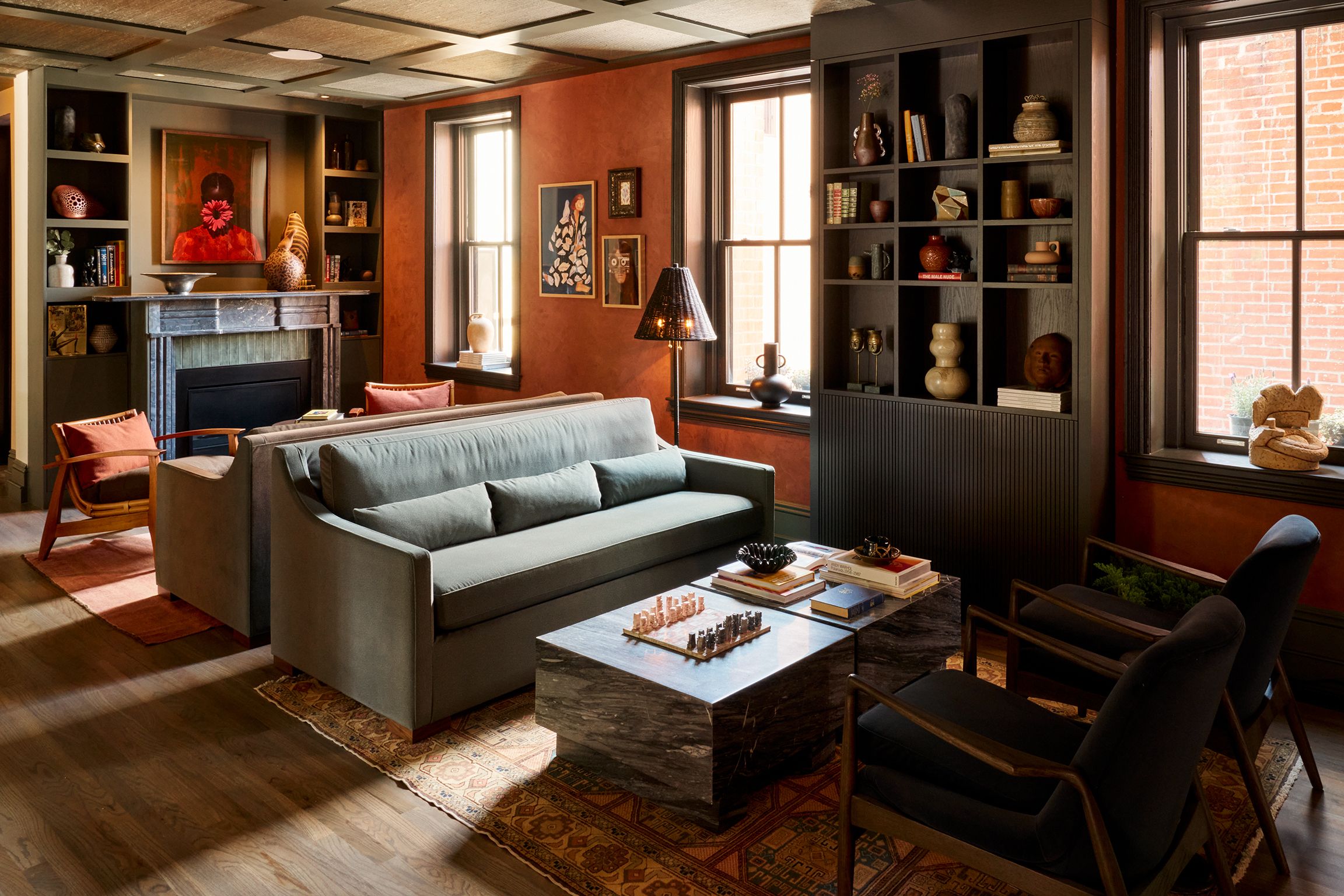 A library area, with green couches and lounge chairs and colorful framed paintings.
