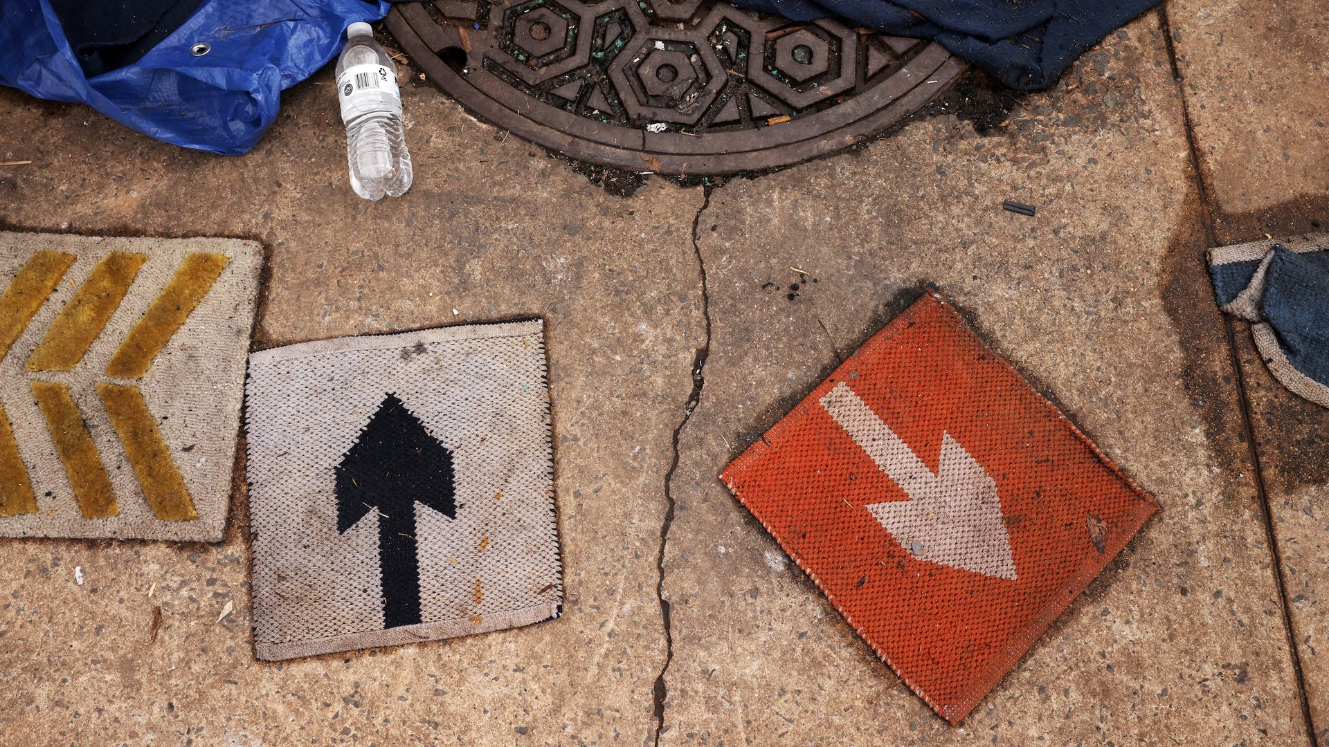 arrows on the ground with a water bottle next to a manhole on a city street