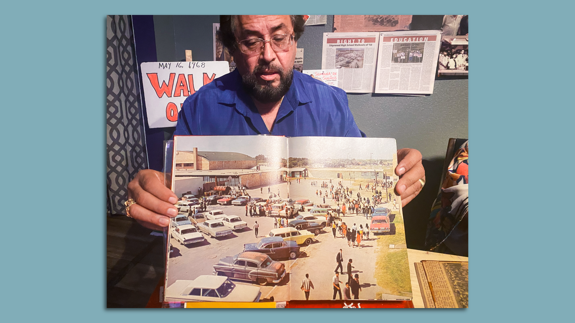 Richard Herrera holds open a 1960s yearbook showing a full spread photo of the Edgewood High School parking lot.