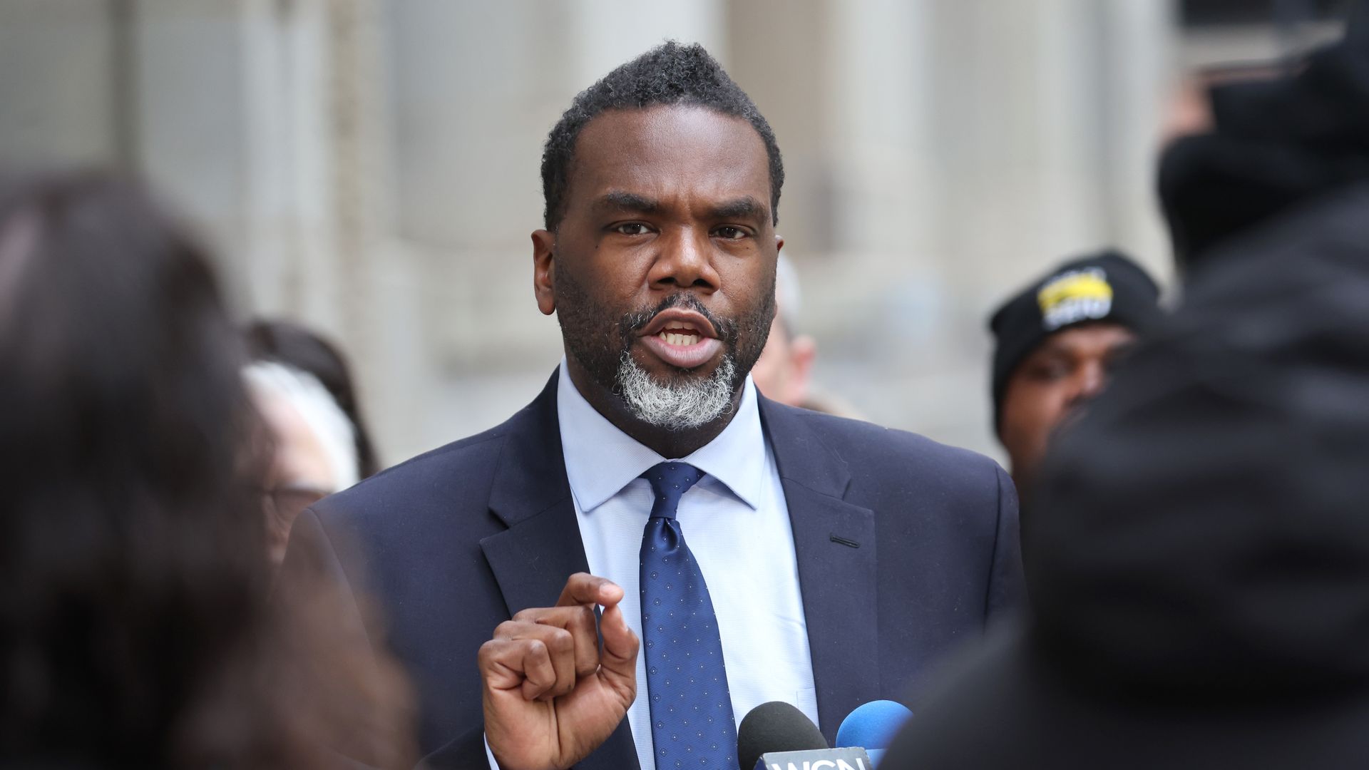 Photo of a man talking to reporters at a press conference