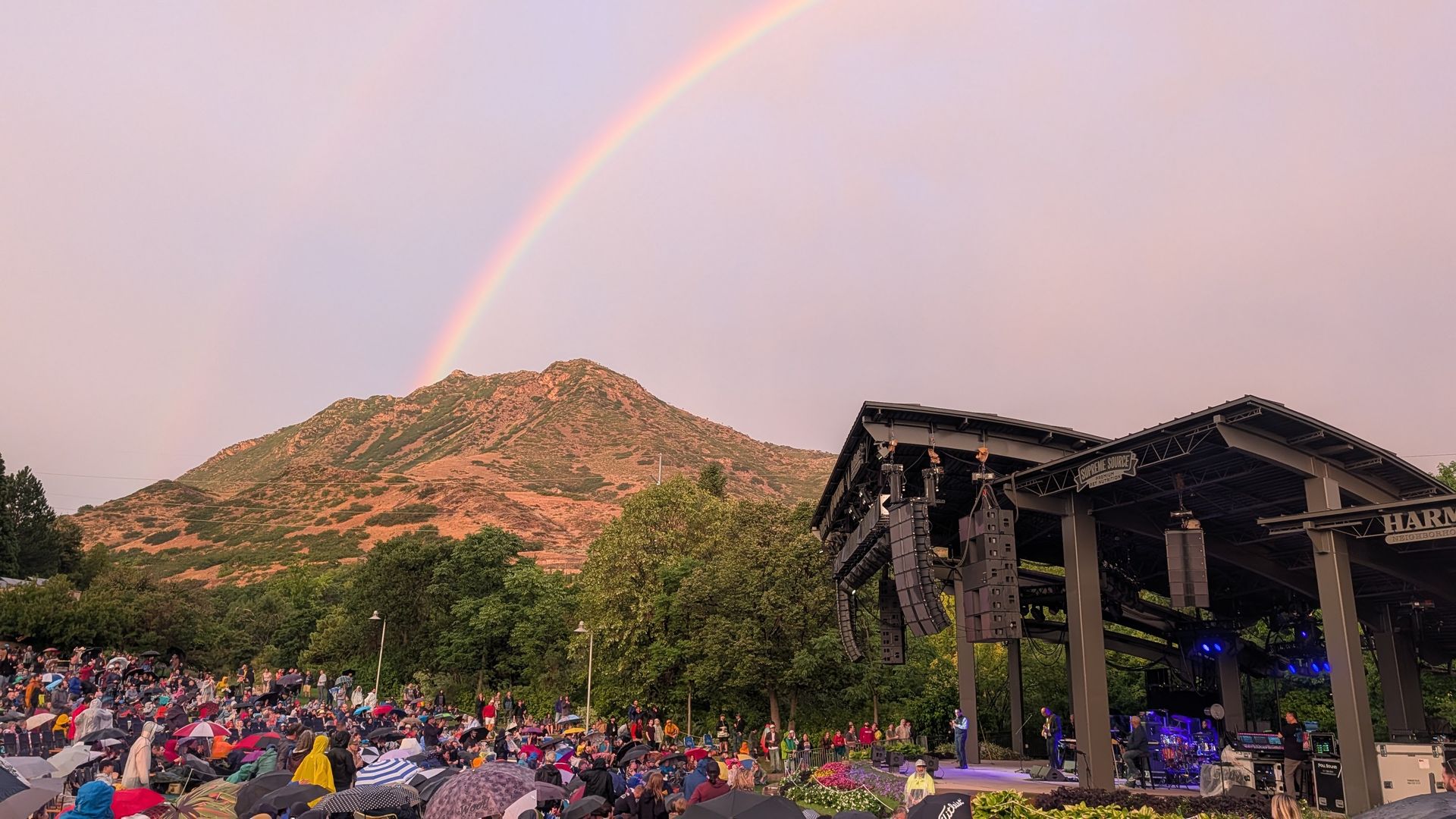 A concert stage with a mountain and rainbow in the background.