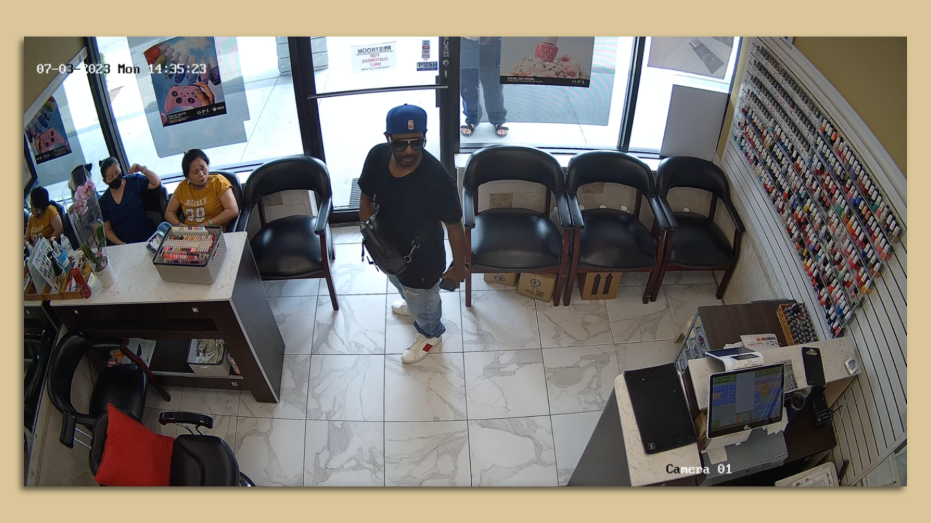 A man wearing sunglasses stands in the waiting area of a nail salon and goes unnoticed by customers