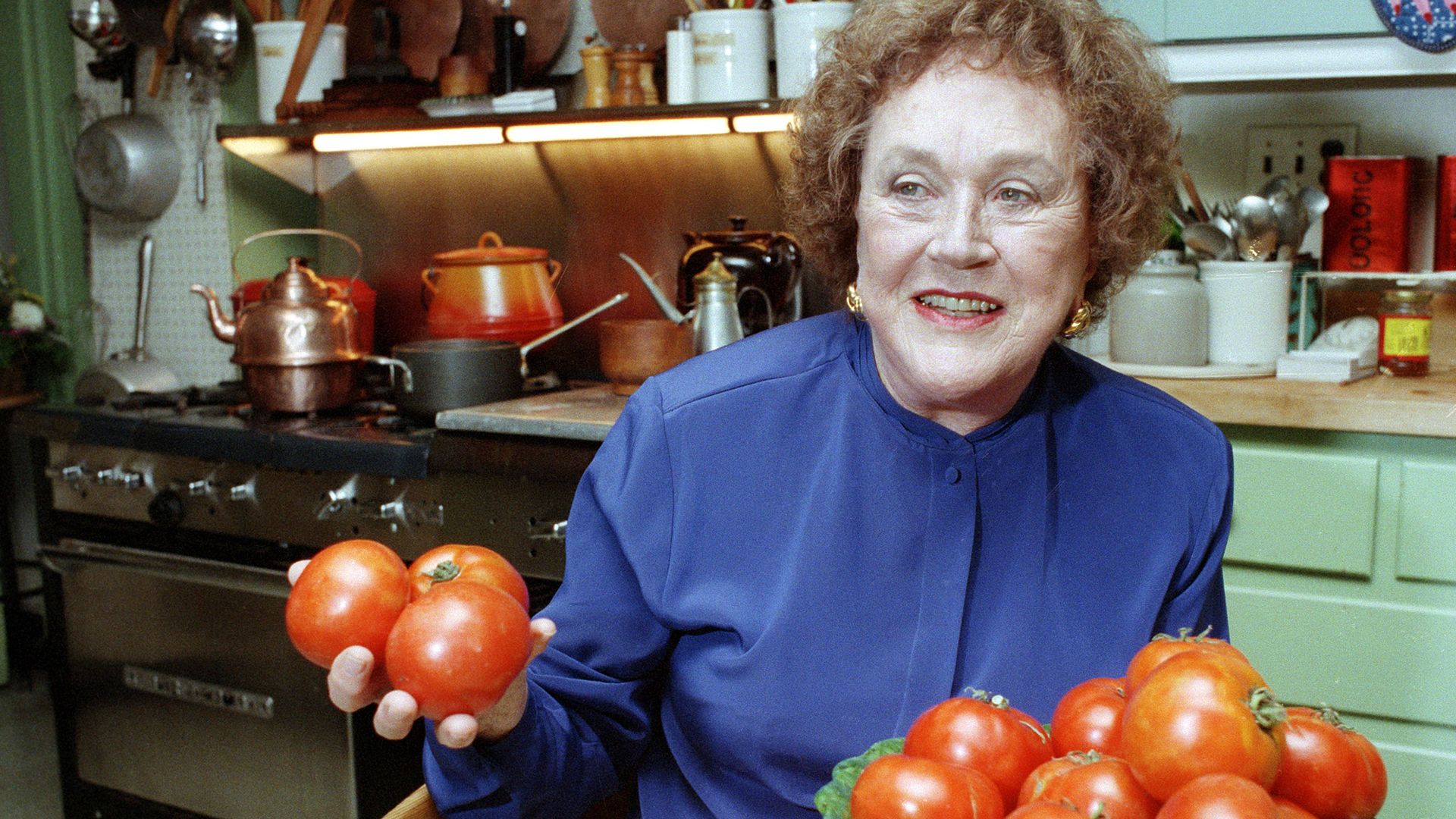 Julia Child with her hands full of tomatoes.
