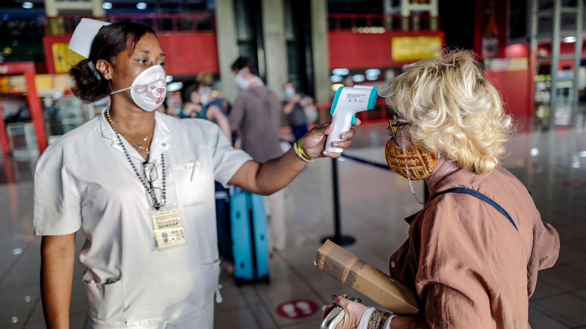 A Cuban nurse checks the temperature of a tourist entering Cuba in the airport