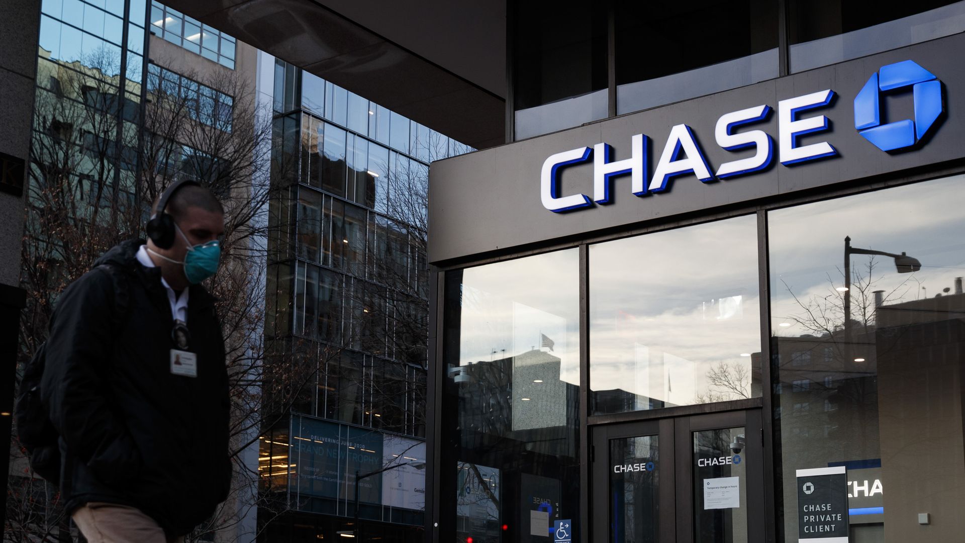 A pedestrian wearing a protective mask walks past a JPMorgan Chase bank branch