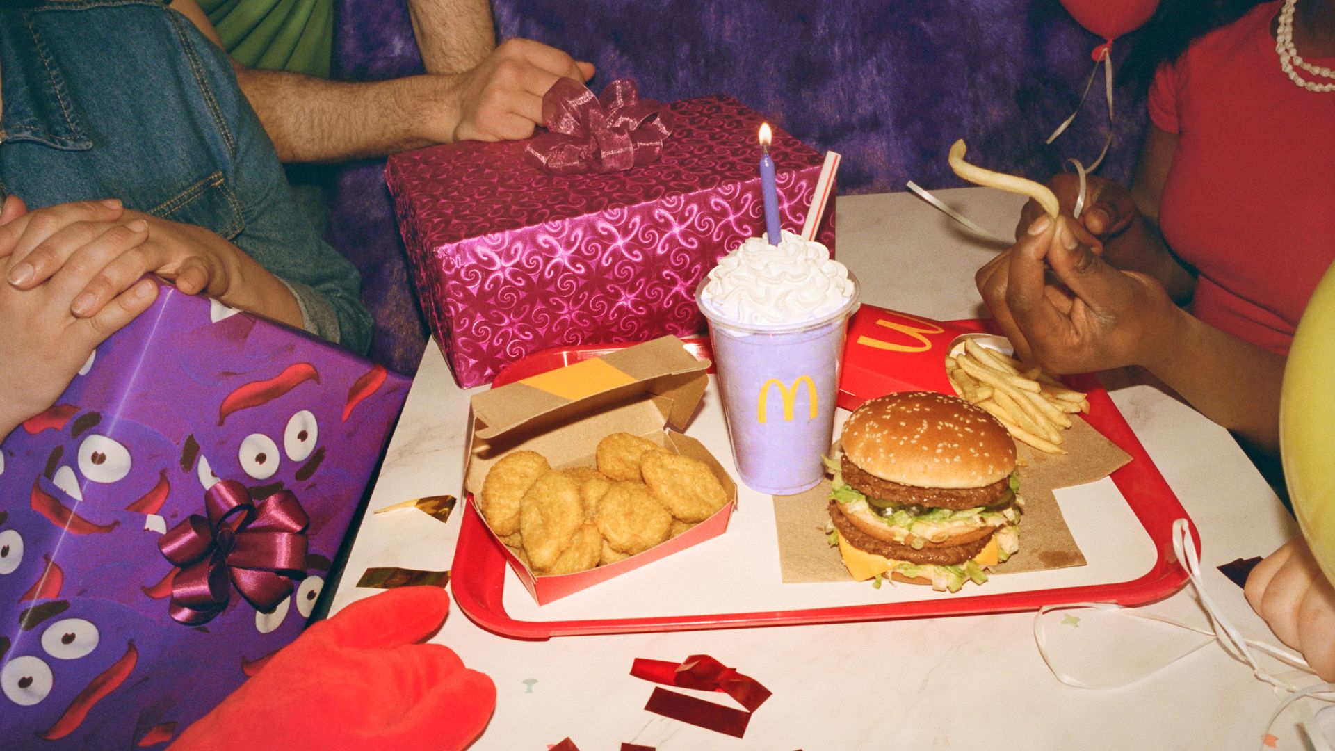 Gifts around a table with McDonald's Chicken McNuggets, a purple shake, Big Mac and fries