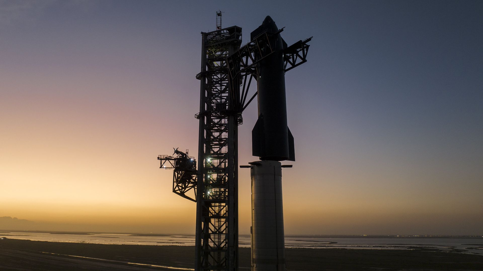 Starship in silhouette against a purple and yellow sky
