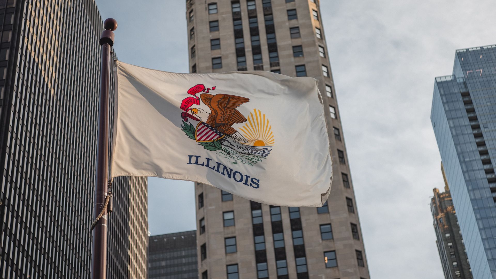 The Illinois state flag waving in front of buildings.