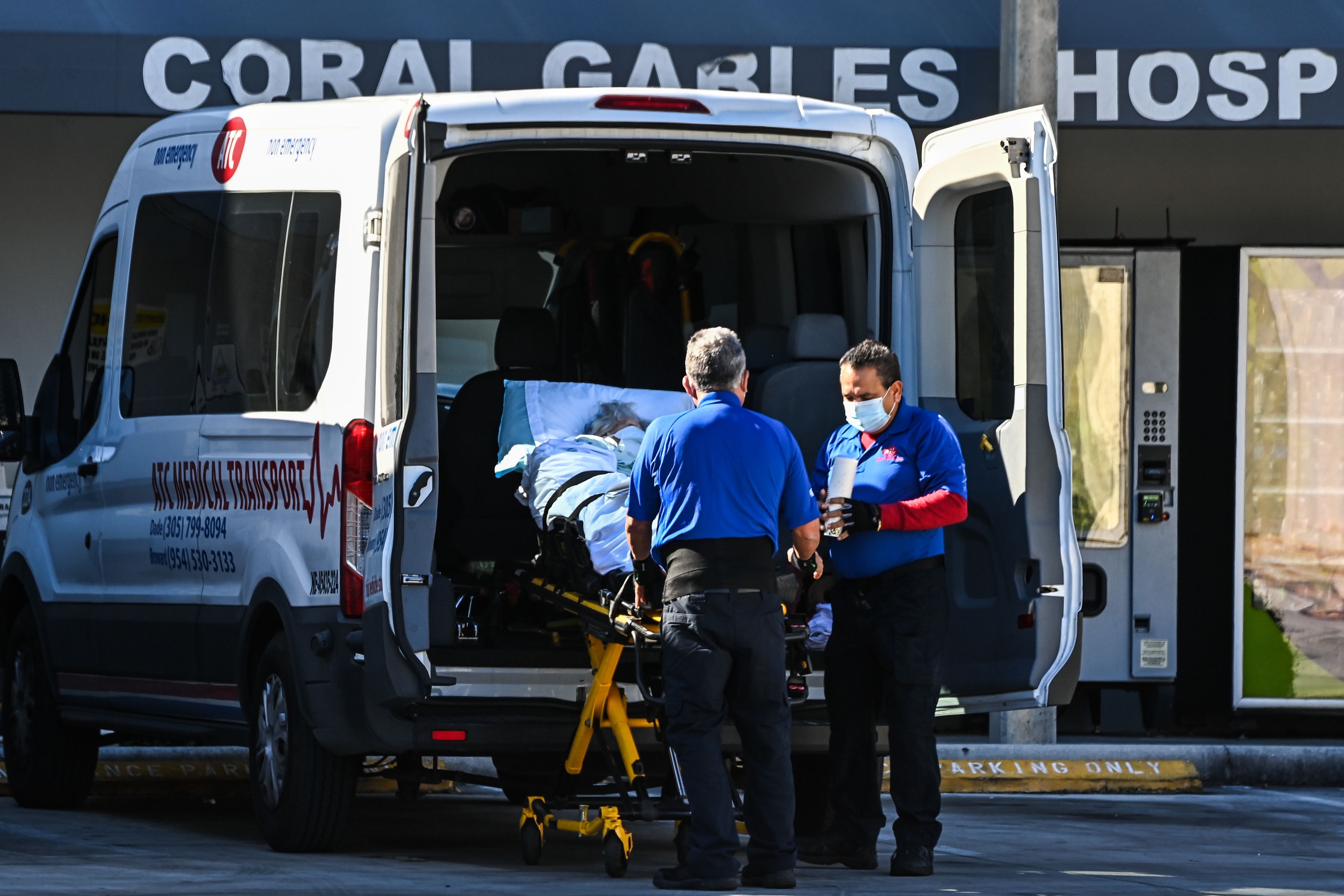 Medics transfer a patient on a stretcher from an ambulance outside of Emergency at Coral Gables Hospital where Coronavirus patients are treated in Coral Gables near Miami, Florida 