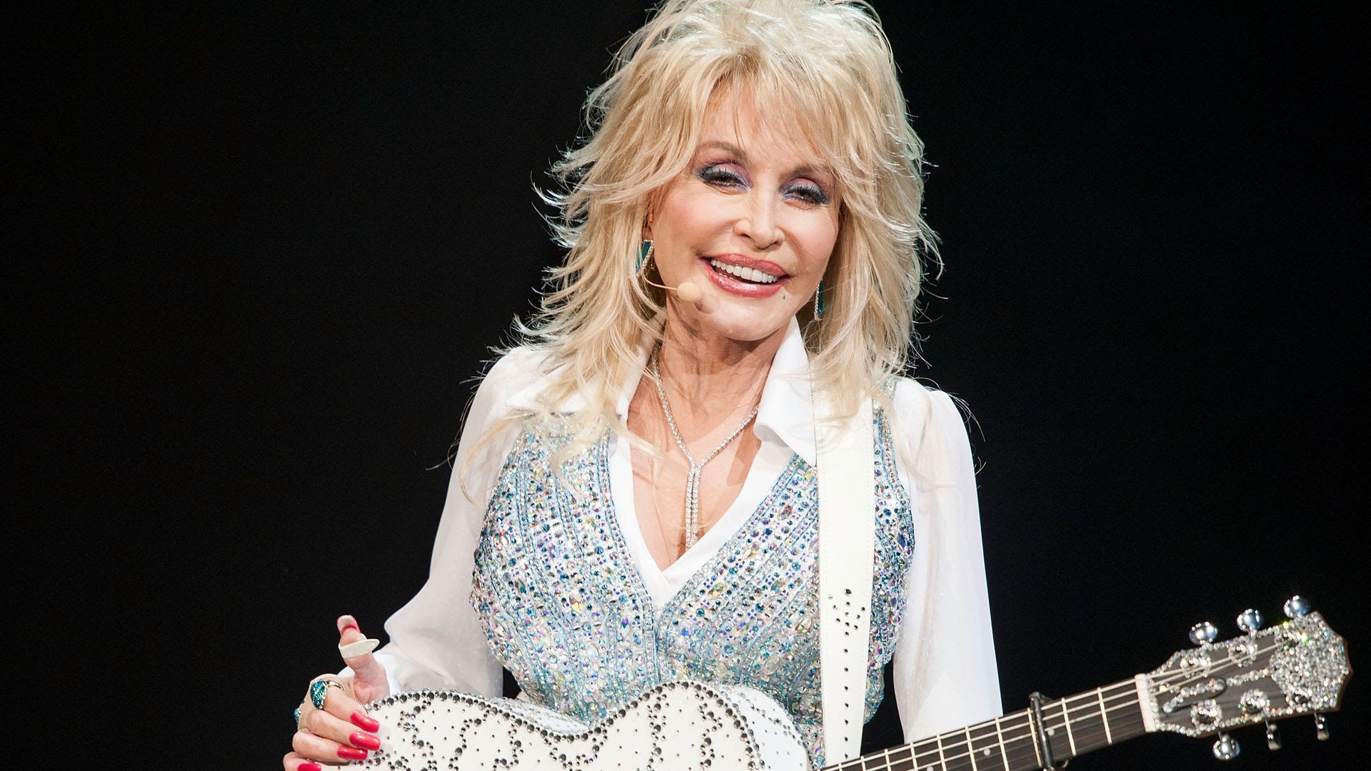 Dolly Parton on stage with a white guitar