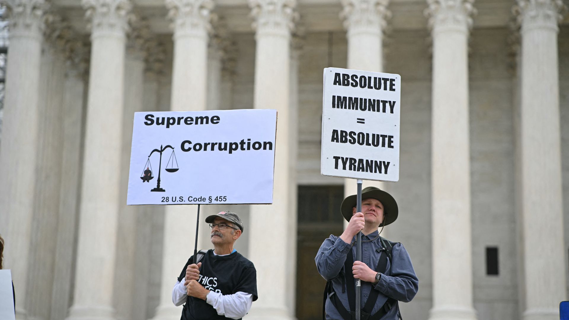 Protesters hold signs outside of the Supreme Court.