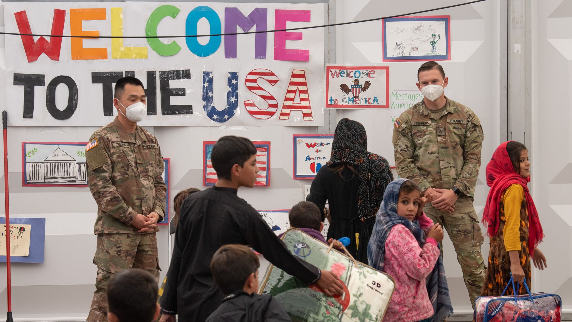 Afghan families walk through the waiting area for departure to the USA