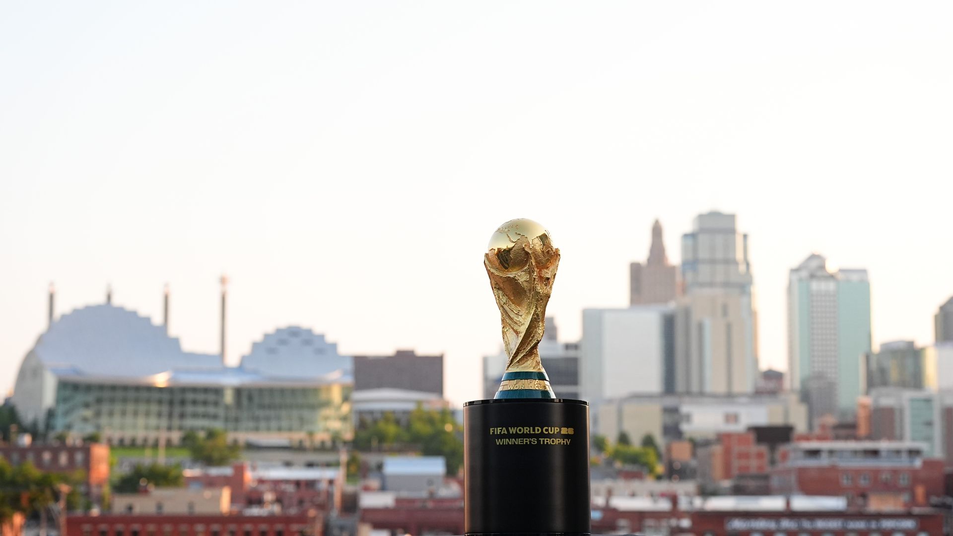 FIFA World Cup men's trophy in the foreground with the Kansas City skyline in the background during the day.