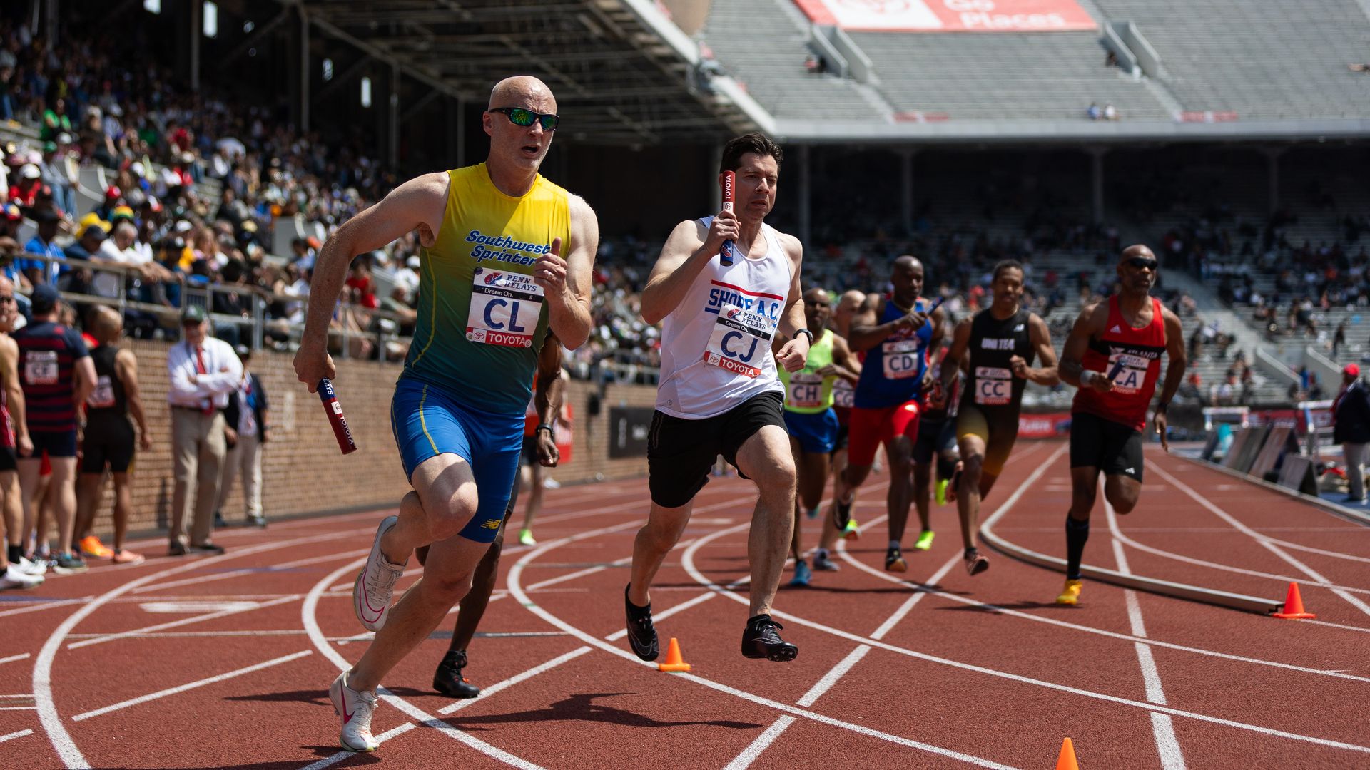 Men running on a track at the Penn Relays.