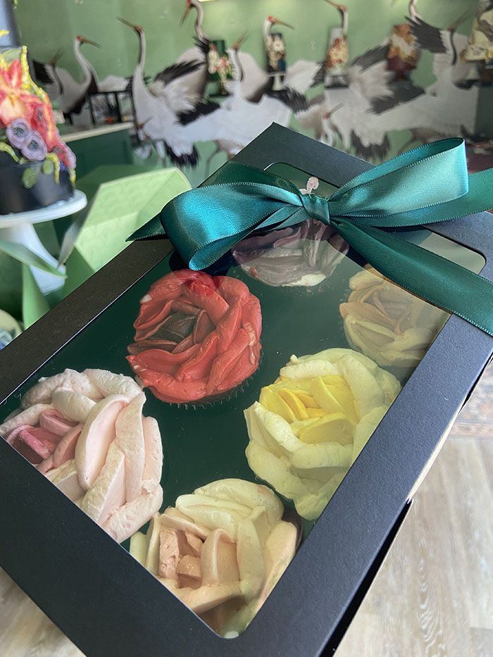 Half-dozen cupcakes with roses on top.