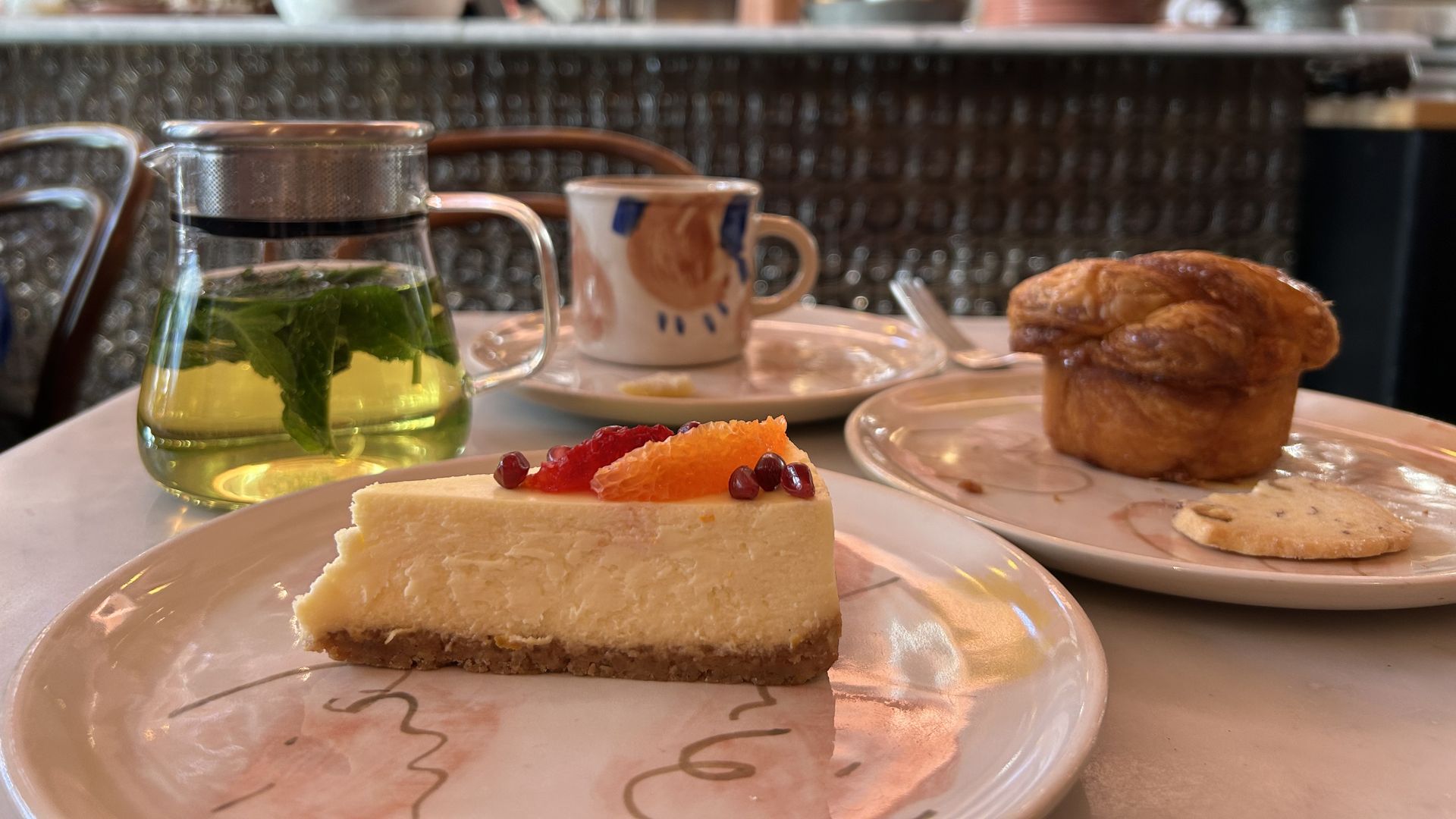 Photo of a slice of cake, a muffin and tea sitting on a table at a cafe