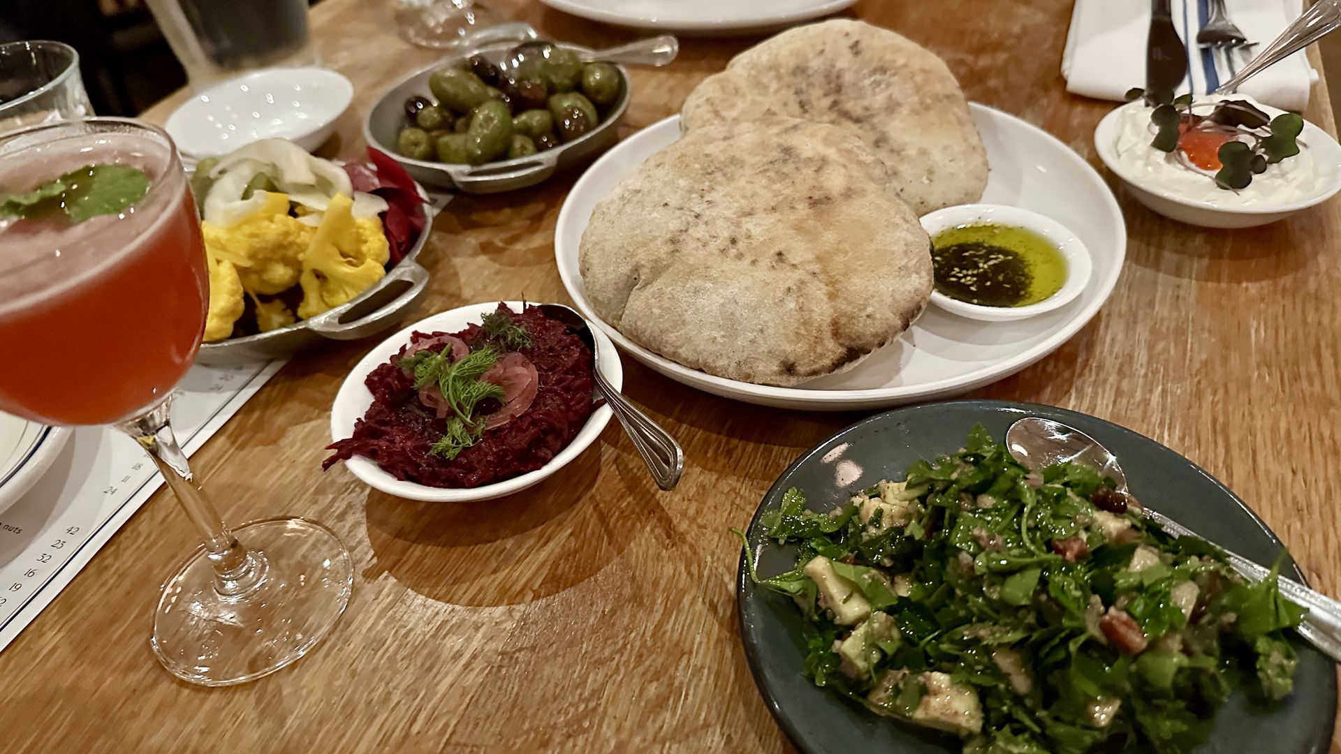 Photo shows a variety of Israeli food on the table, including homemade pita.