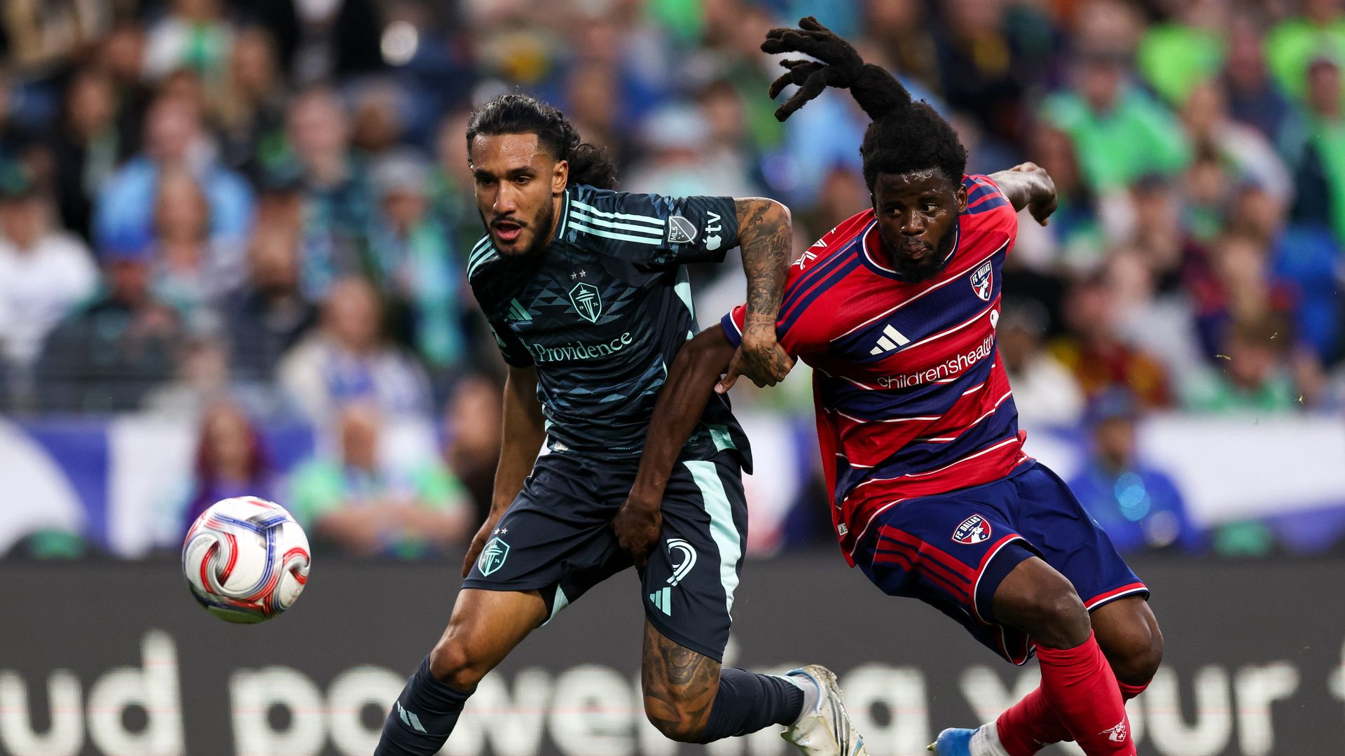 Two sMLS occer players battler over the ball during a match.