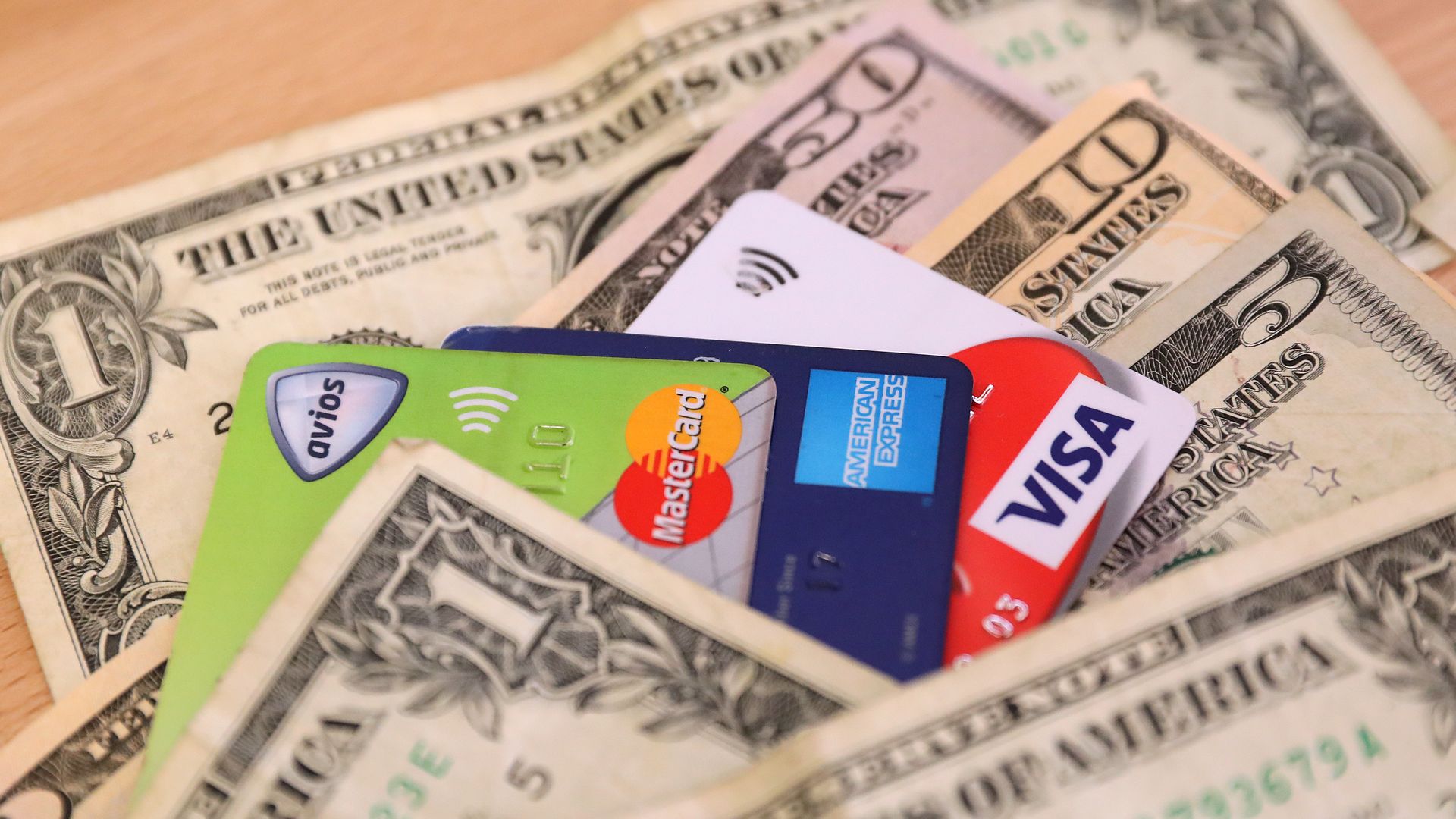 AmericanExpress, Visa and Mastercard credit cards on top of a pile of cash.