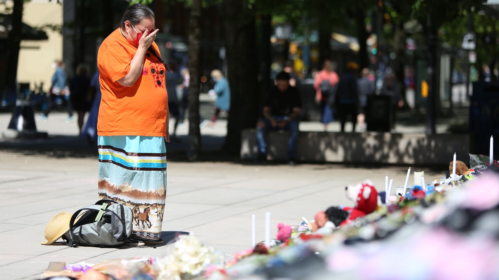 A woman mourns over 215 pairs of kids shoes outside Vancouver Art Gallery during a memorial on May 29, 2021 in Vancouver, British Columbia, Canada