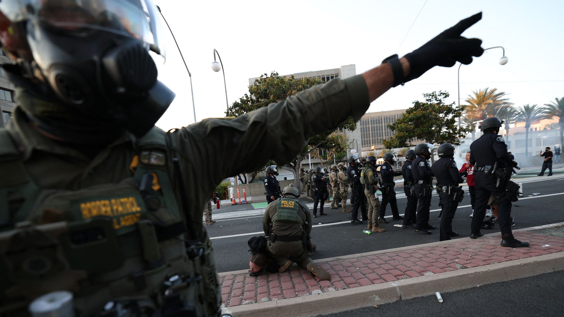 A Border Patrol agent gestures near another arresting a protester near the United States Citizenship and Immigration Services (USCIS) Santa Ana Field Office after protesters gathered following reports of Immigration and Customs Enforcement (ICE) raids in Santa Ana, California, on June 9, 2025